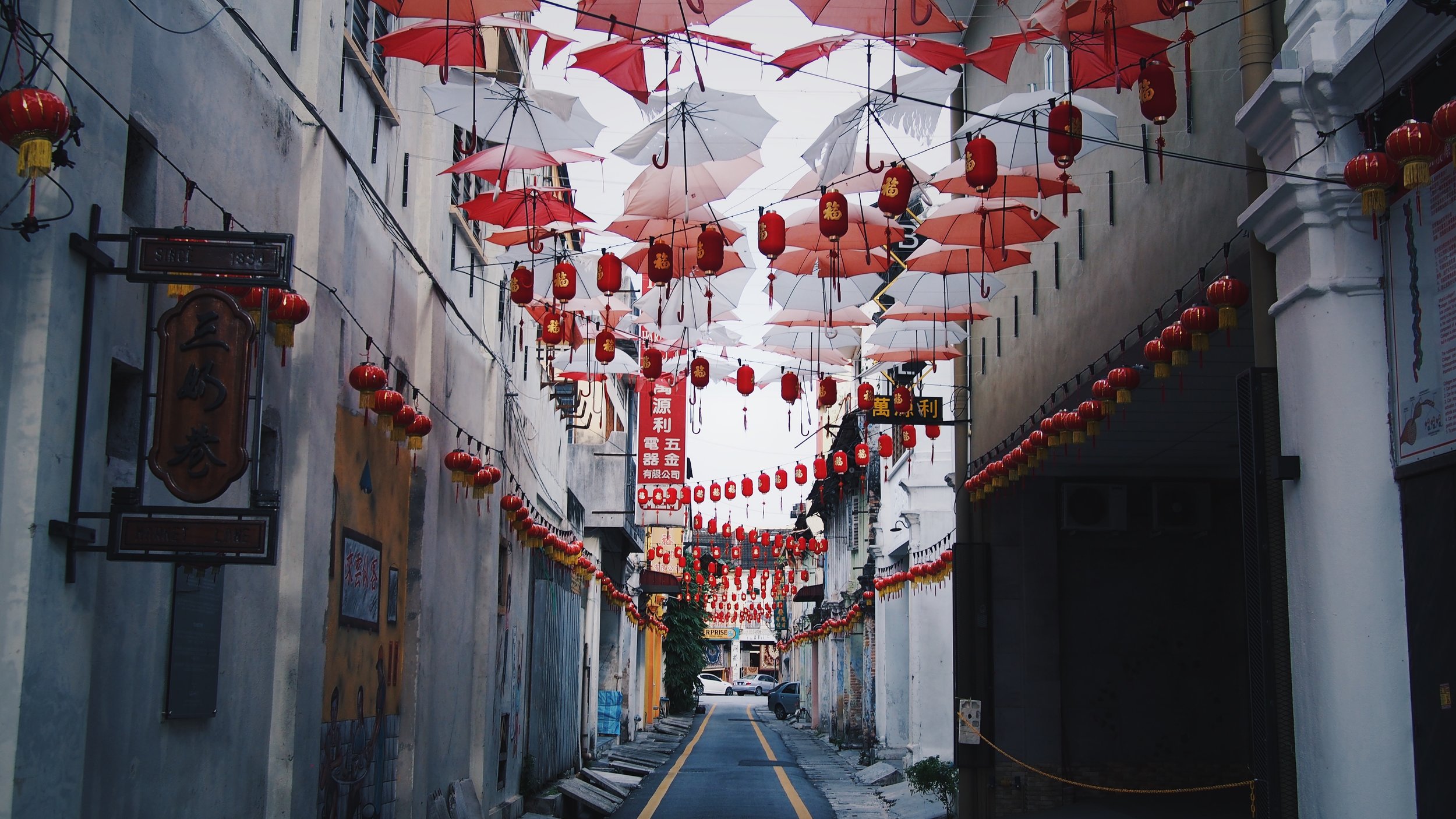Red and white umbrellas hanging above a street in Ipoh, Malaysia