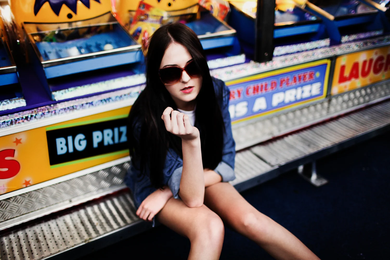 Brisbane, QLD Australia Fashion Photographer Stacey Russell || Fashion Photography Model Photoshoot || Brown hair girl sitting near clown game at The Ekka Show wearing denim jacket and sunglasses