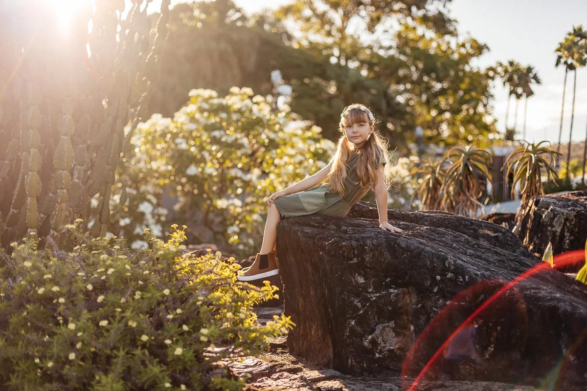 Brisbane Model Photographer Stacey Russell || Professional Australia Fashion Photography Modelling Photoshoot || Model portfolio image of girl sitting on rock in gardens, sun flare