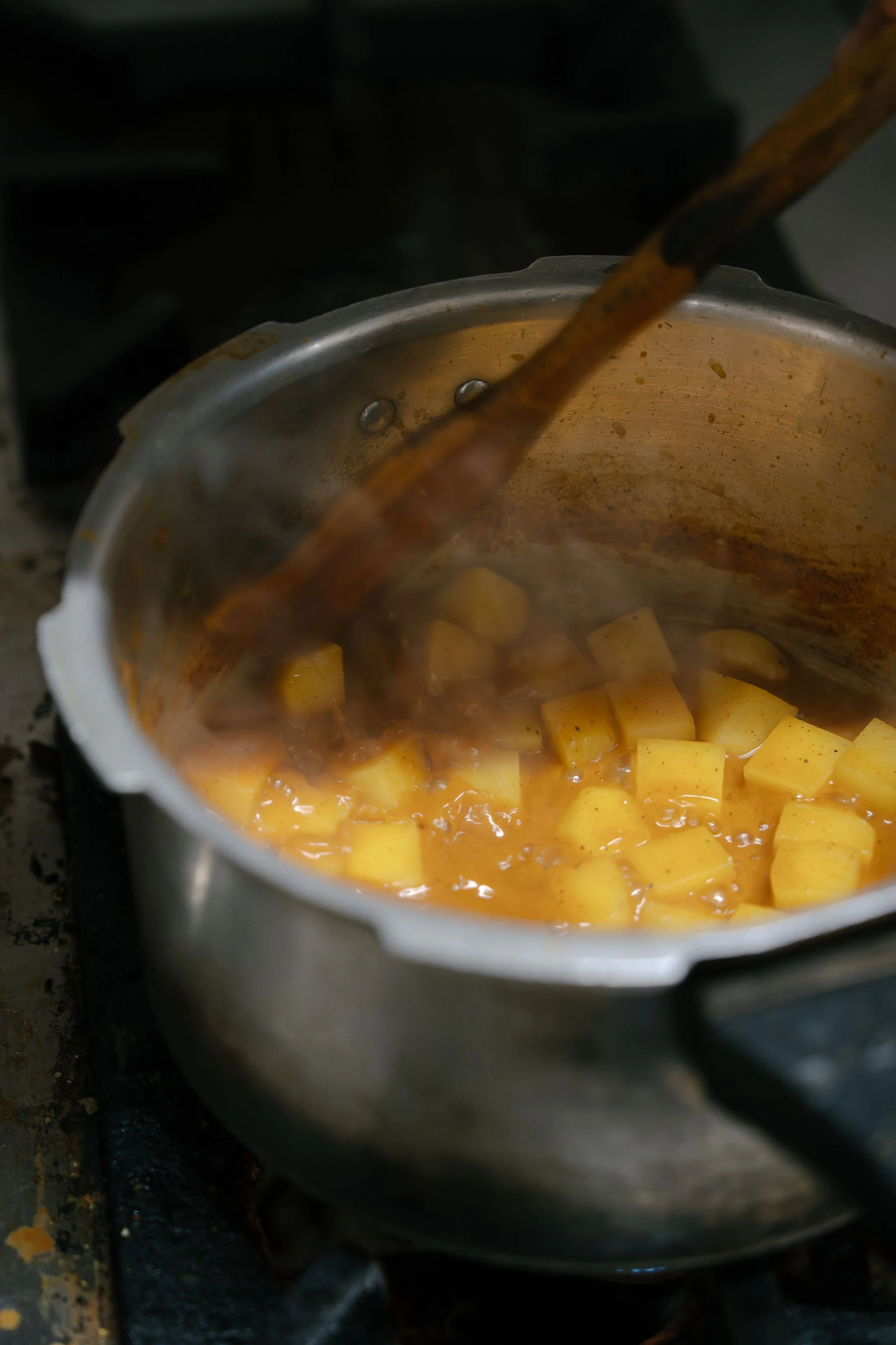 Pot of boiling diced potatoes cooking on a stove, with steam rising.
