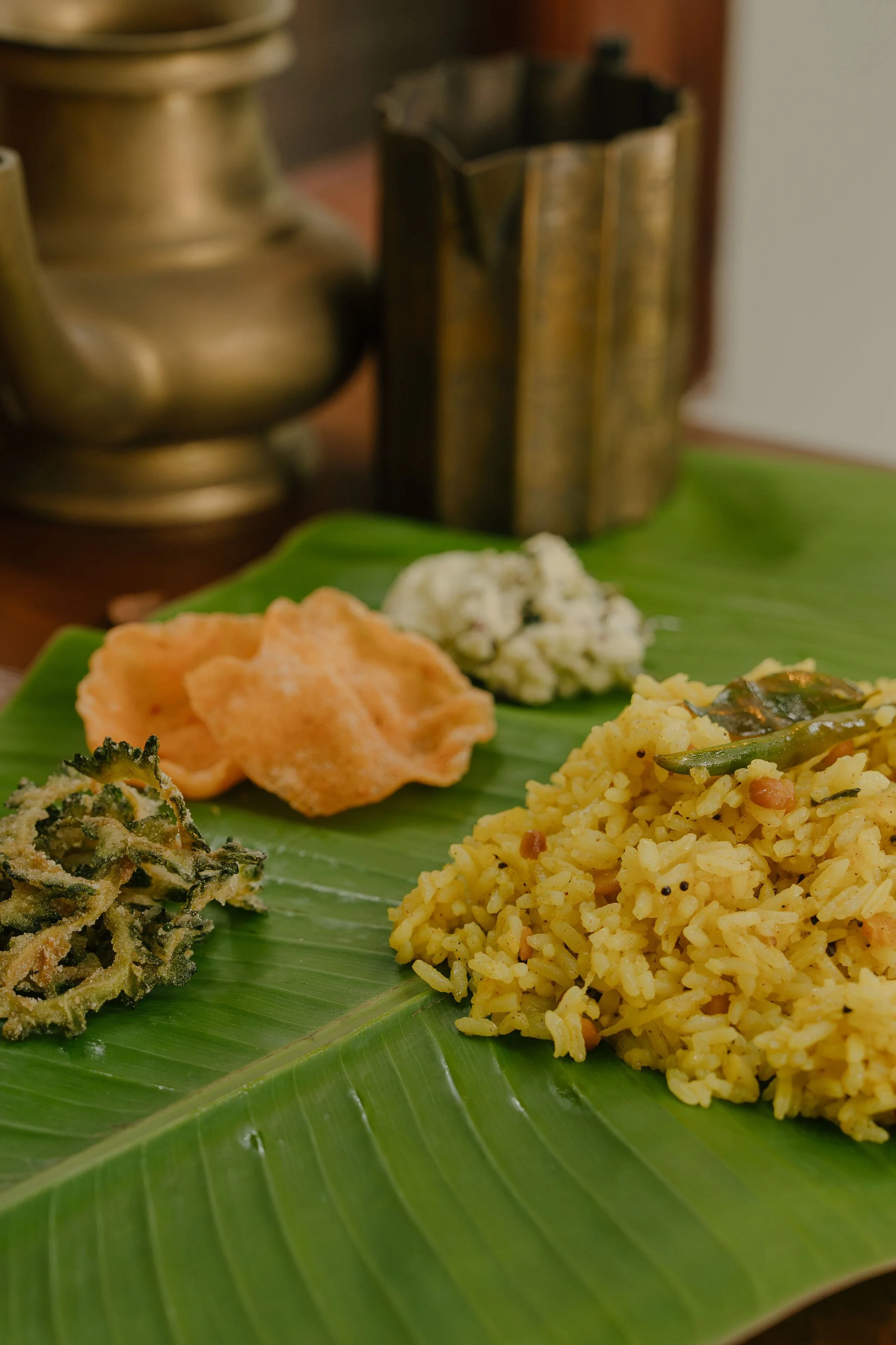 Traditional Indian meal served on a banana leaf, including rice, vegetables, and pickles.