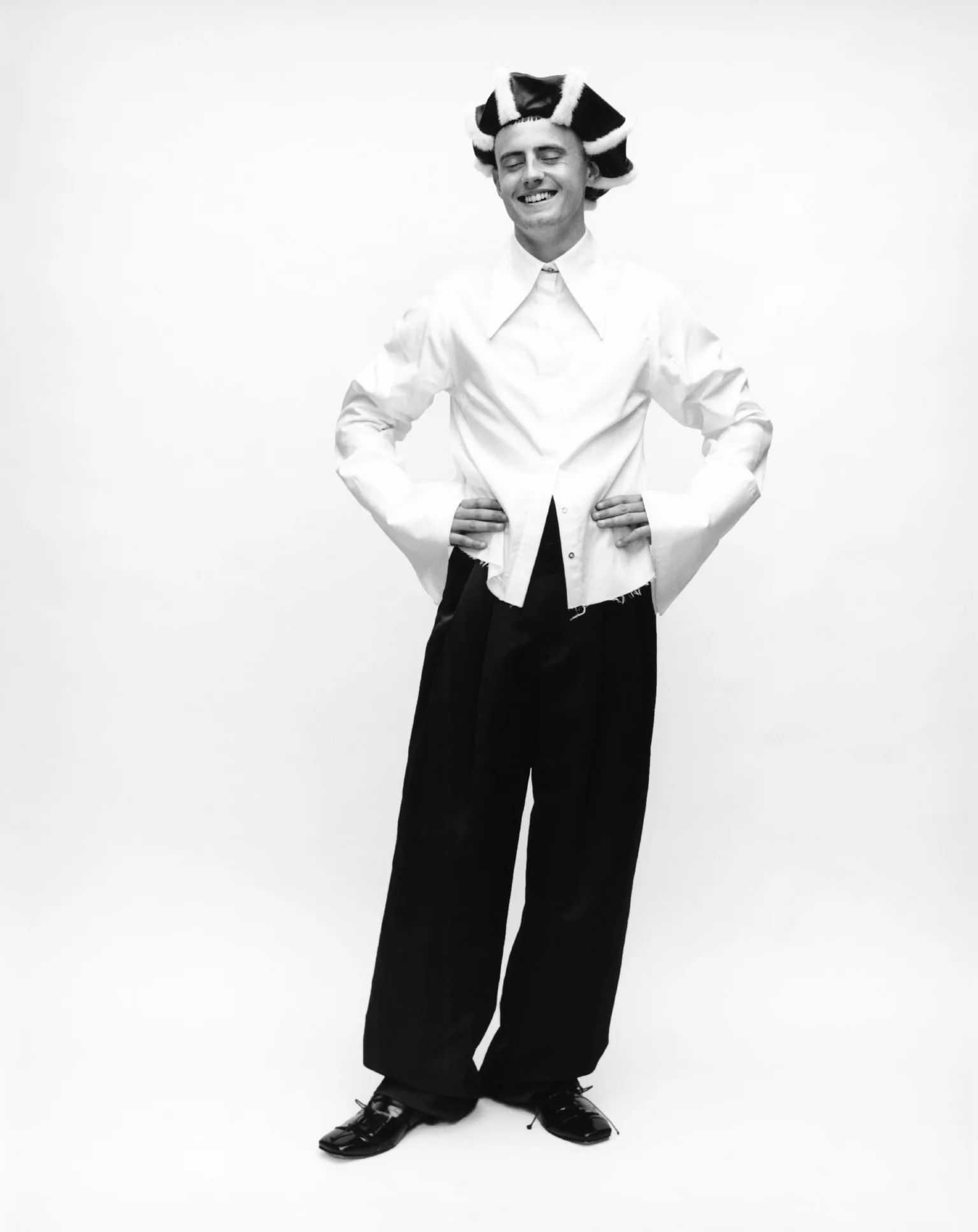 Cae viste camisa de MARQUES ALMEIDA, pantalón de WOOYOUNGMI, zapatos de CHARLES JEFFREY LOVERBOY y sombrero de NOEL STEWART. 