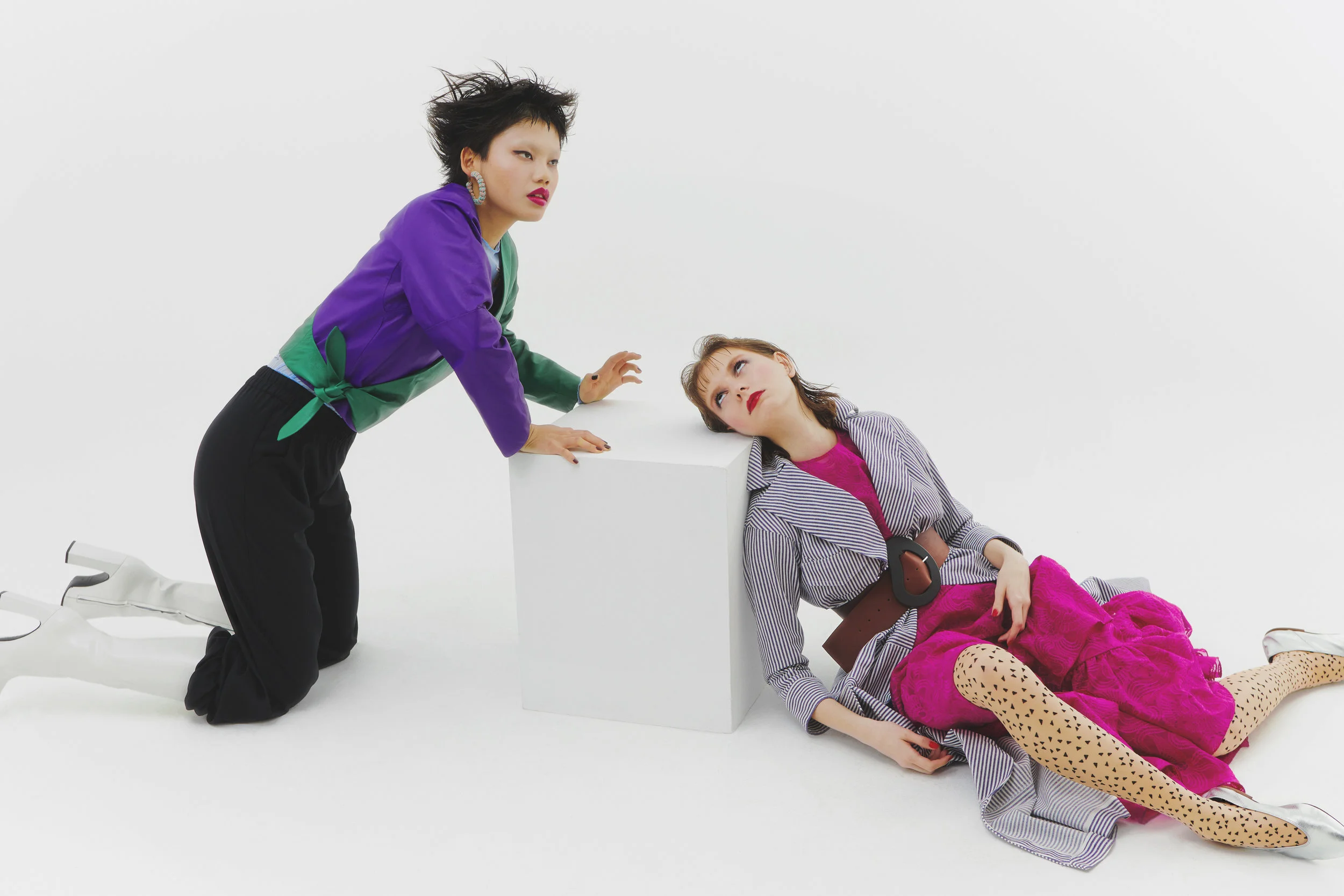 Izquierda: Pendientes de BALABOOSTÉ , top de MARTIAL CHARASSE , chaqueta de PIHAKAPI , pantalón de VICTORIA TOMAS y zapatos de BALENCIAGA . Derecha: Abrigo de JUNKO SHIMADA , vestido de KENZO , cinturón de TIBI , medias de WOLFORD y zapatos de SOLOVIERE .