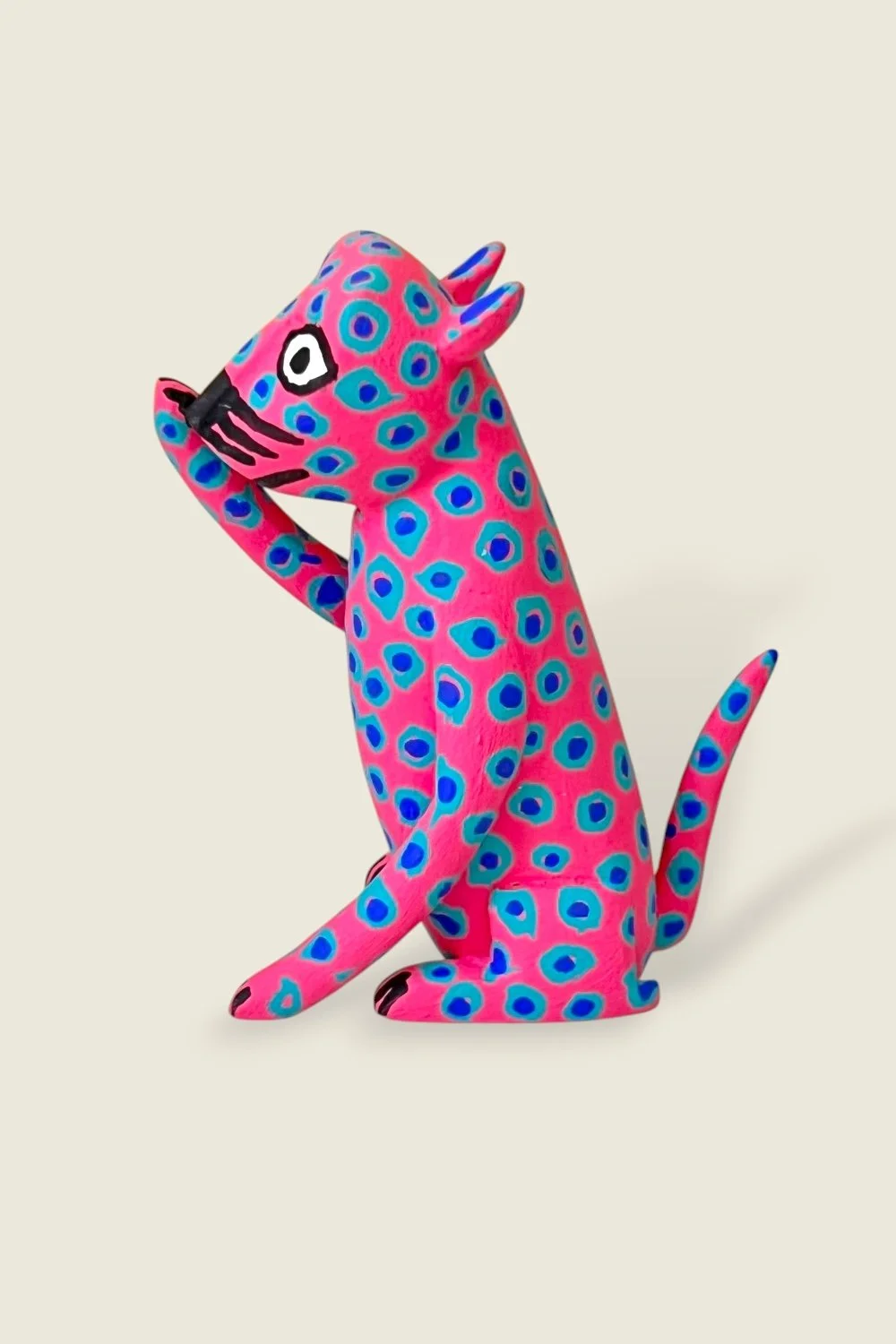 Pink cat licking it's paw alebrije