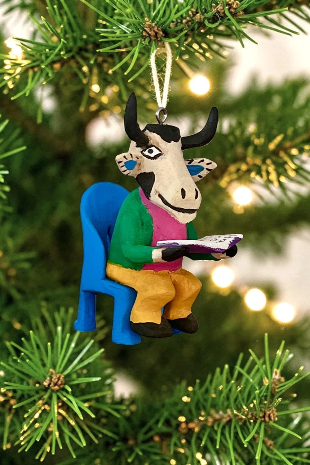 Mexican folk art carved steer reading in a chair ornament