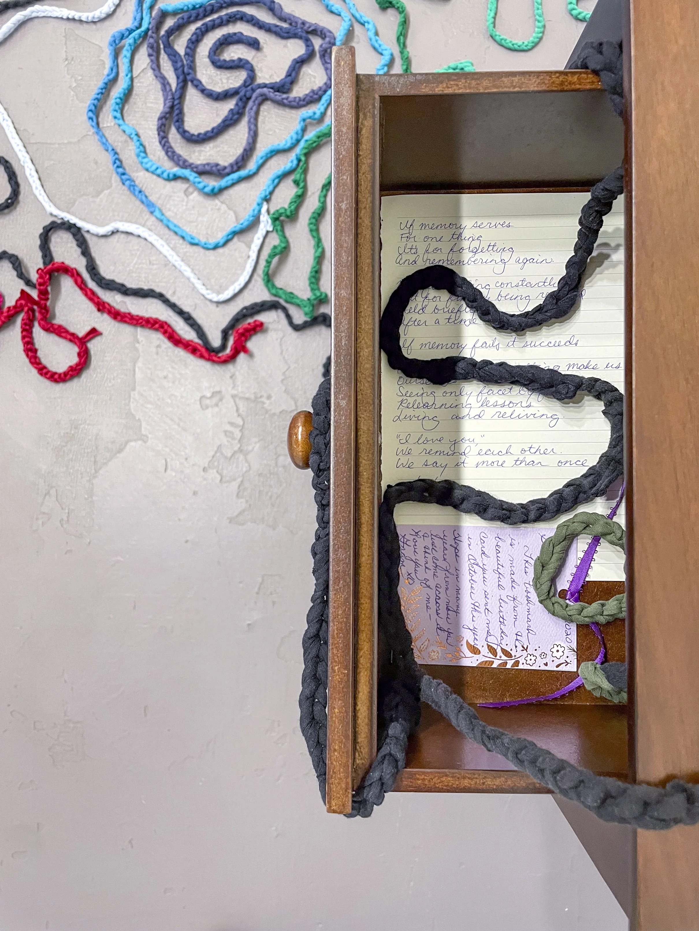  Samantha Mack, detail of  Time and Distance,  2026. Dimensions variable, Two nightstands; two yellow trivets (one made by artist, one made by her great grandmother); threadbare hand-me-downs, cut and crocheted; chiming Regulator clock; antique book 