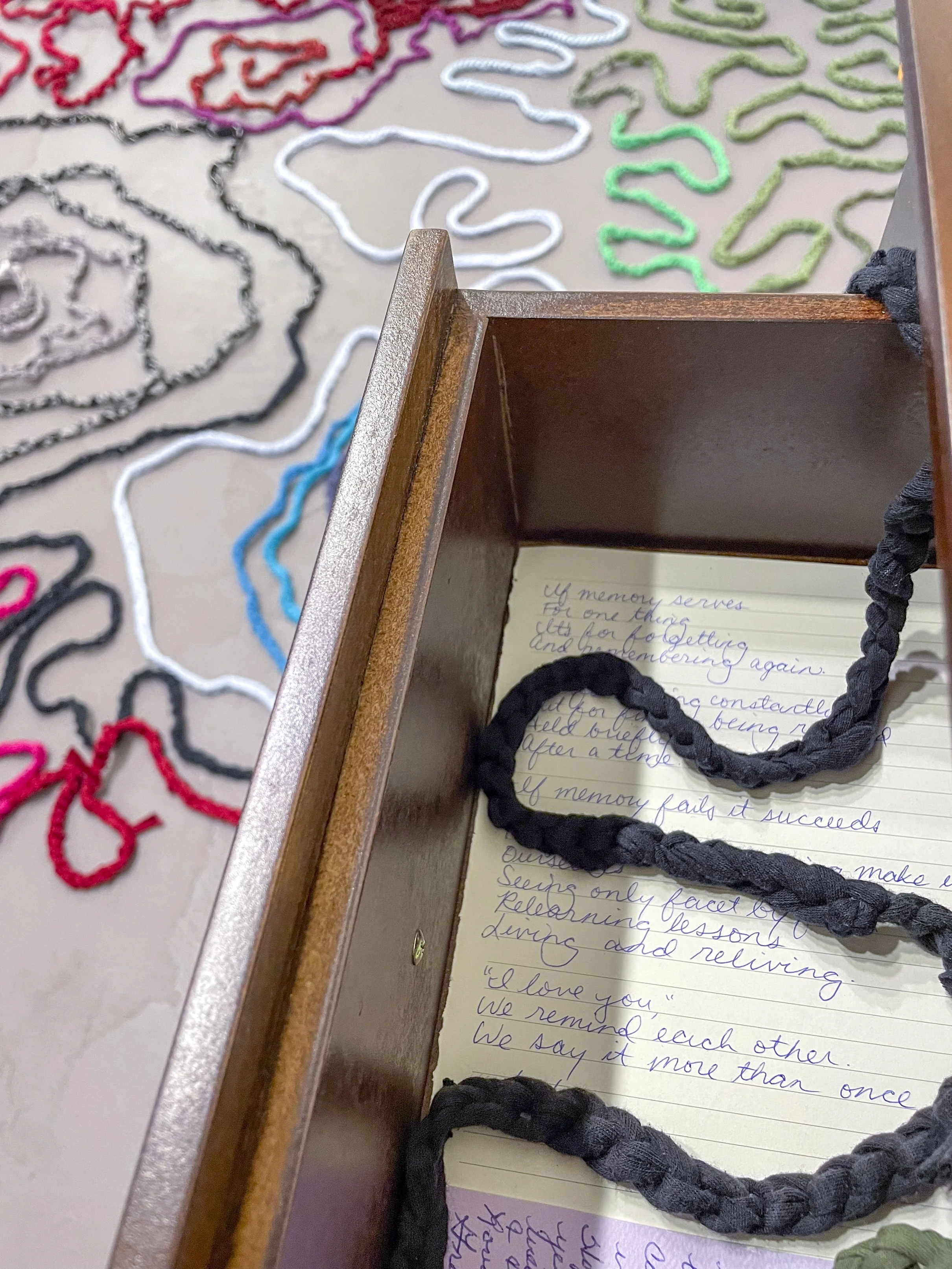  Samantha Mack, detail of  Time and Distance,  2026. Dimensions variable, Two nightstands; two yellow trivets (one made by artist, one made by her great grandmother); threadbare hand-me-downs, cut and crocheted; chiming Regulator clock; antique book 