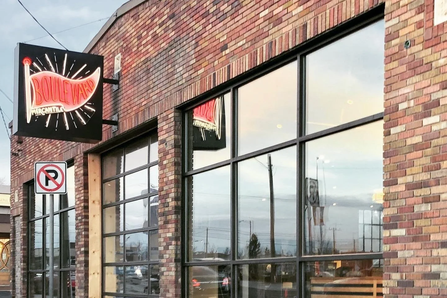 Exterior of a Mercantile store called Boulevard with a brick facade, large glass windows, and a neon sign.