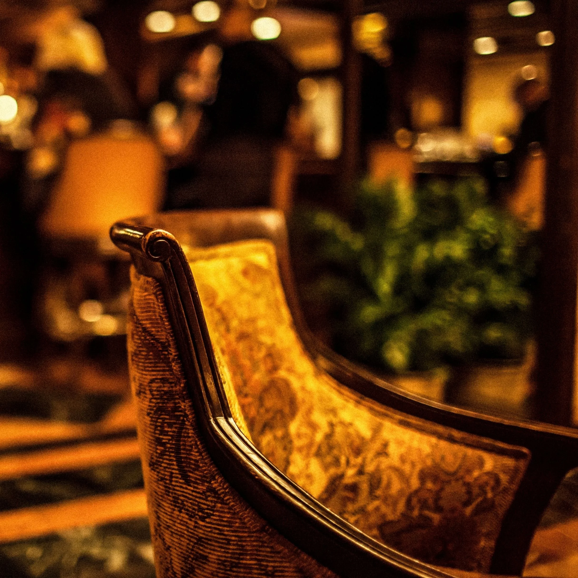 A close-up of a fork resting on a woven placemat in front of a mirror, with warm, blurred lighting in the background, likely in a restaurant or dining setting.