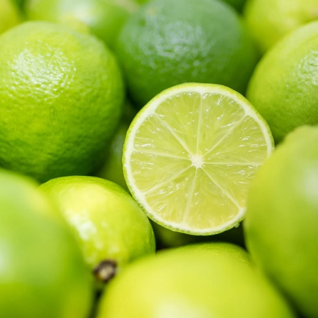 Close-up of a halved lime surrounded by whole limes.