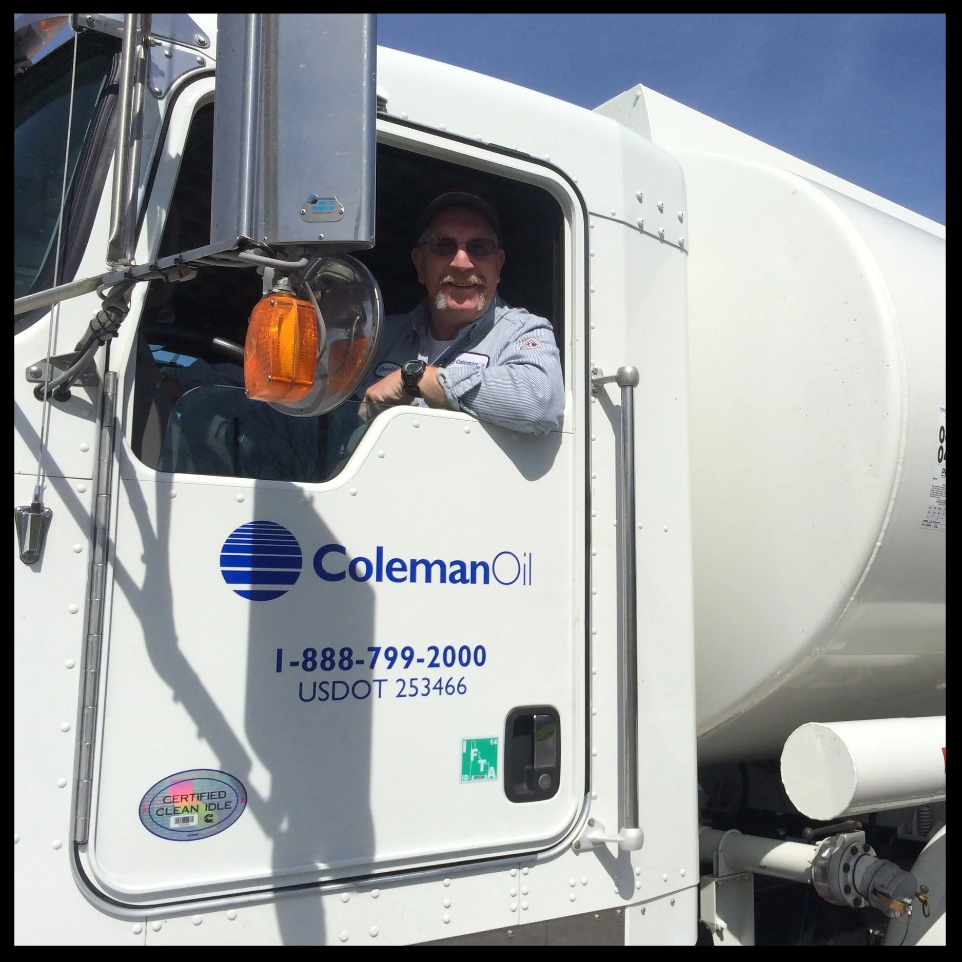 A friendly Coleman Oil driver smiles from the cab of his truck. 