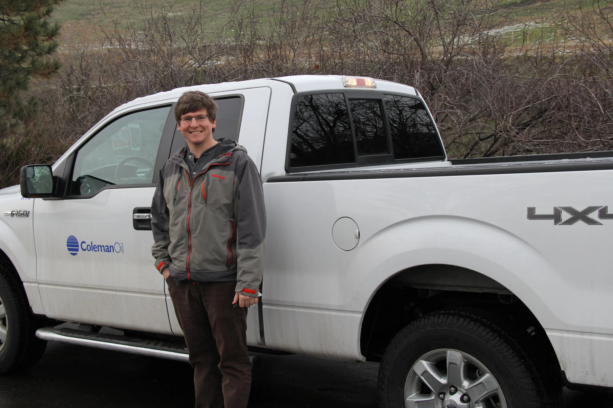 A Coleman Oil employee smiles in front of a Coleman Oil pick up truck. It's all in a day's work. 