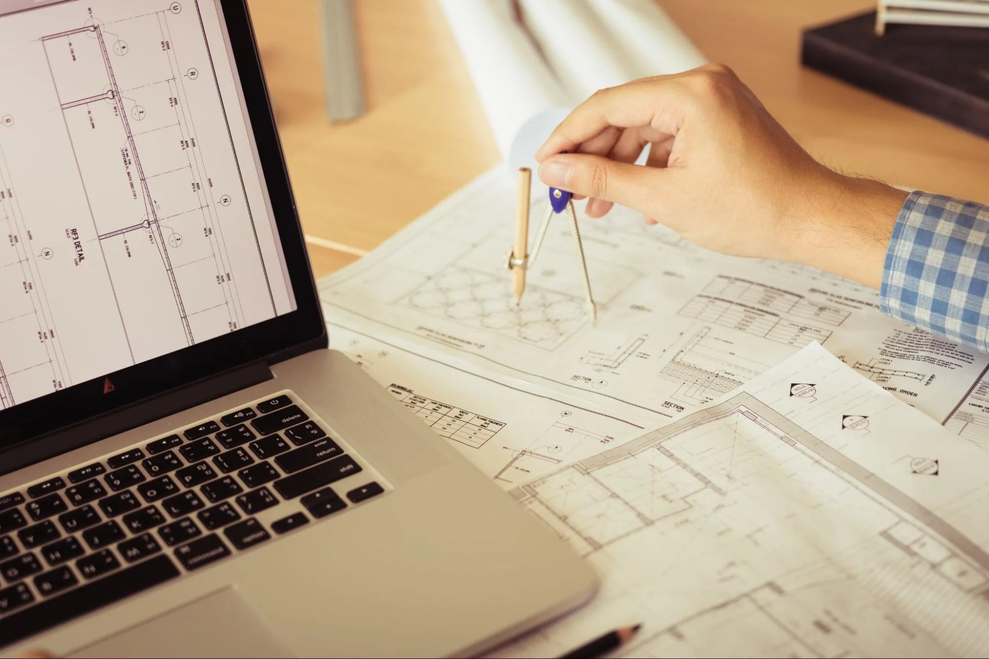 Architect using computer-aided design software and traditional drafting tools to develop detailed site plans and technical blueprints