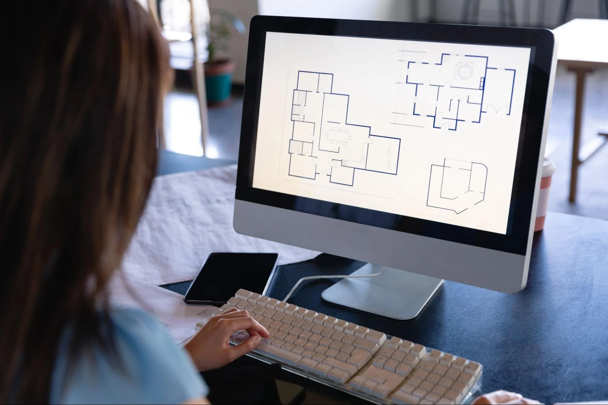 A professional CAD drafting company architect reviews the digital construction plans and technical building drawings on her computer