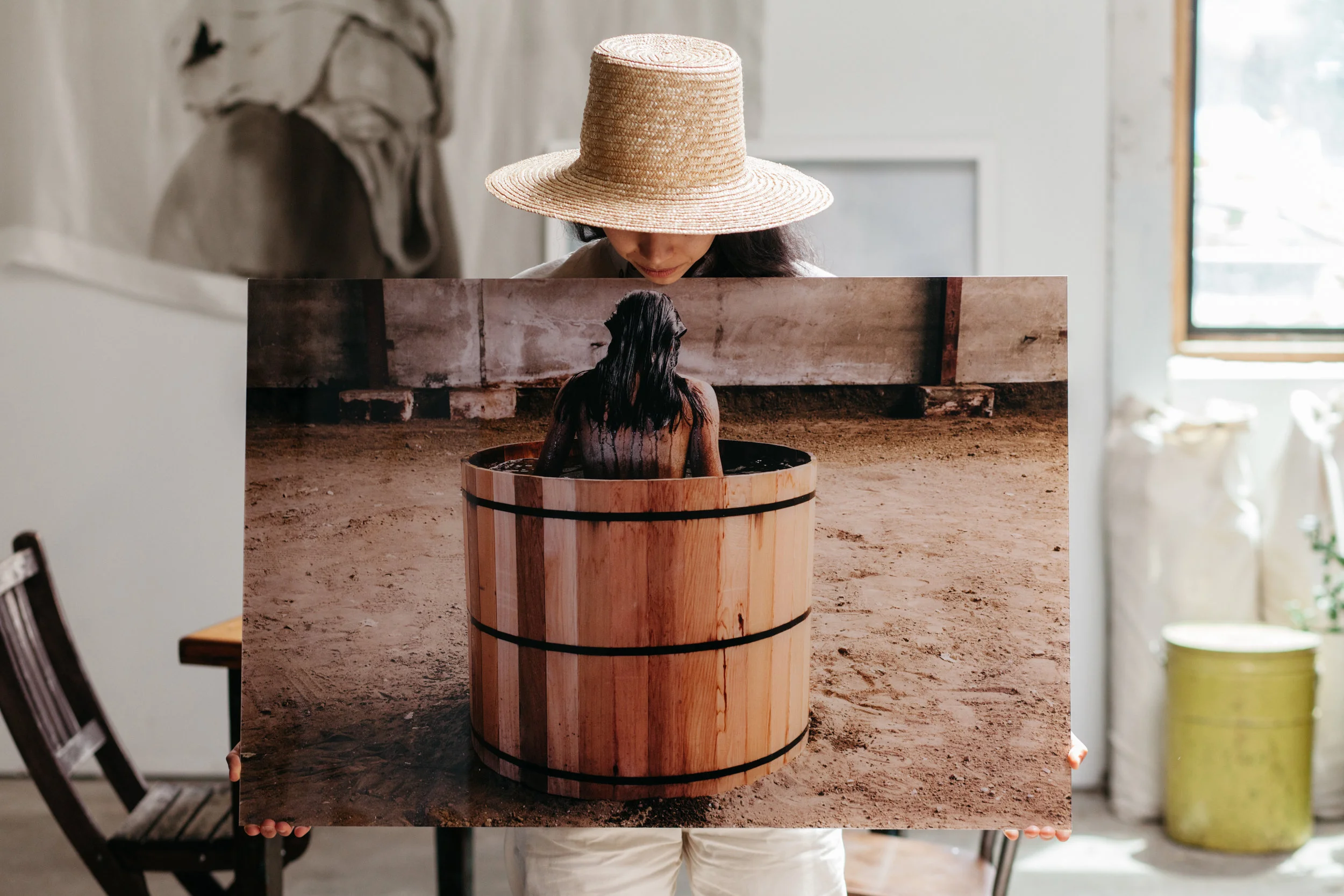 Person holding a large photograph of a woman in a wooden hot tub.