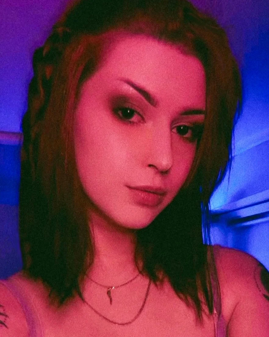 A photo of Jenna in front of a pink light with a blue glow visible in the background