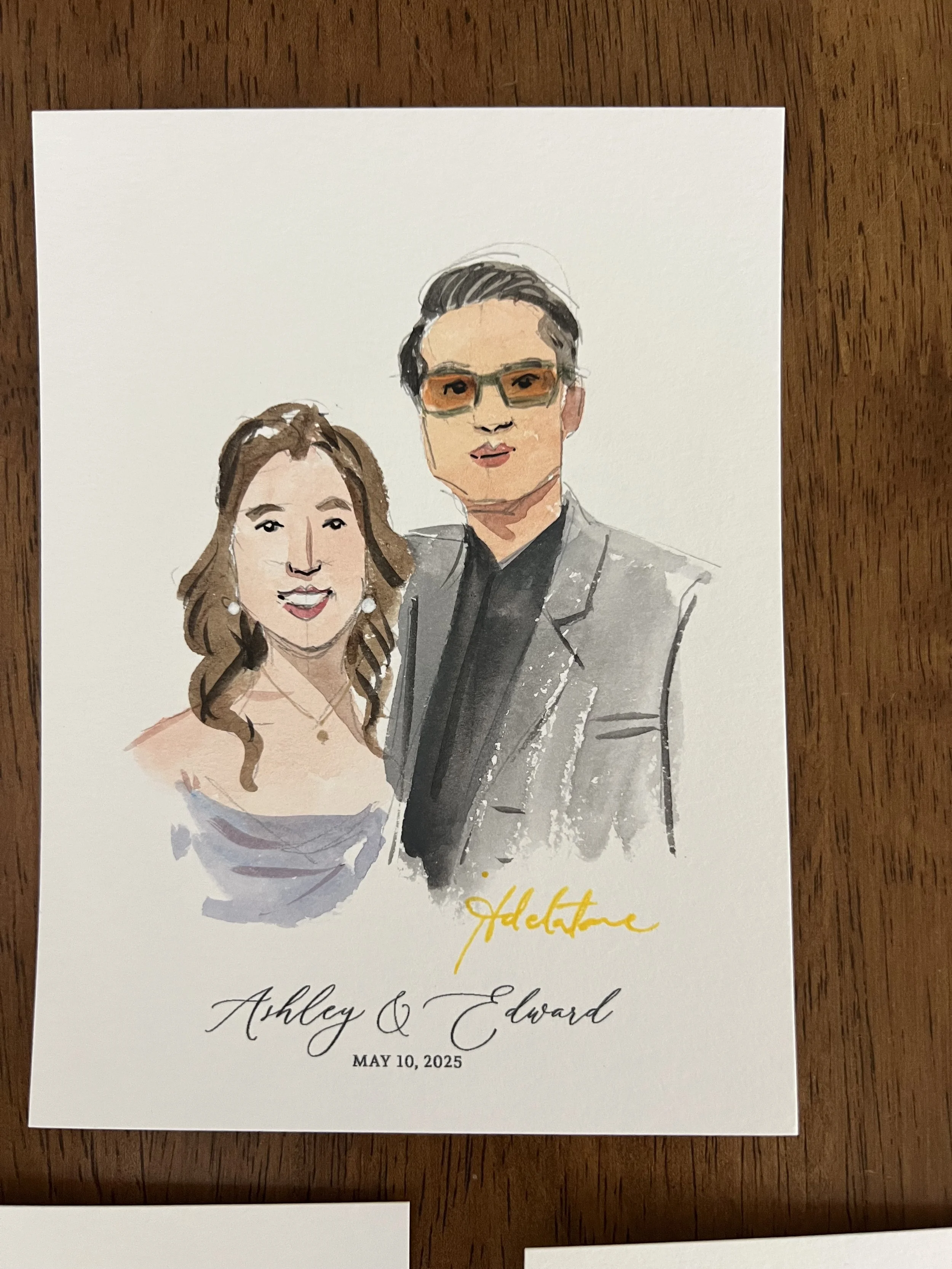 A watercolor illustration of a man and woman at a wedding, with the woman wearing a strapless dress and the man in a gray suit with sunglasses. Below the illustration, the text reads 'Celebrate Ashley & Edward, May 10, 2025,' with the word 'celebrate