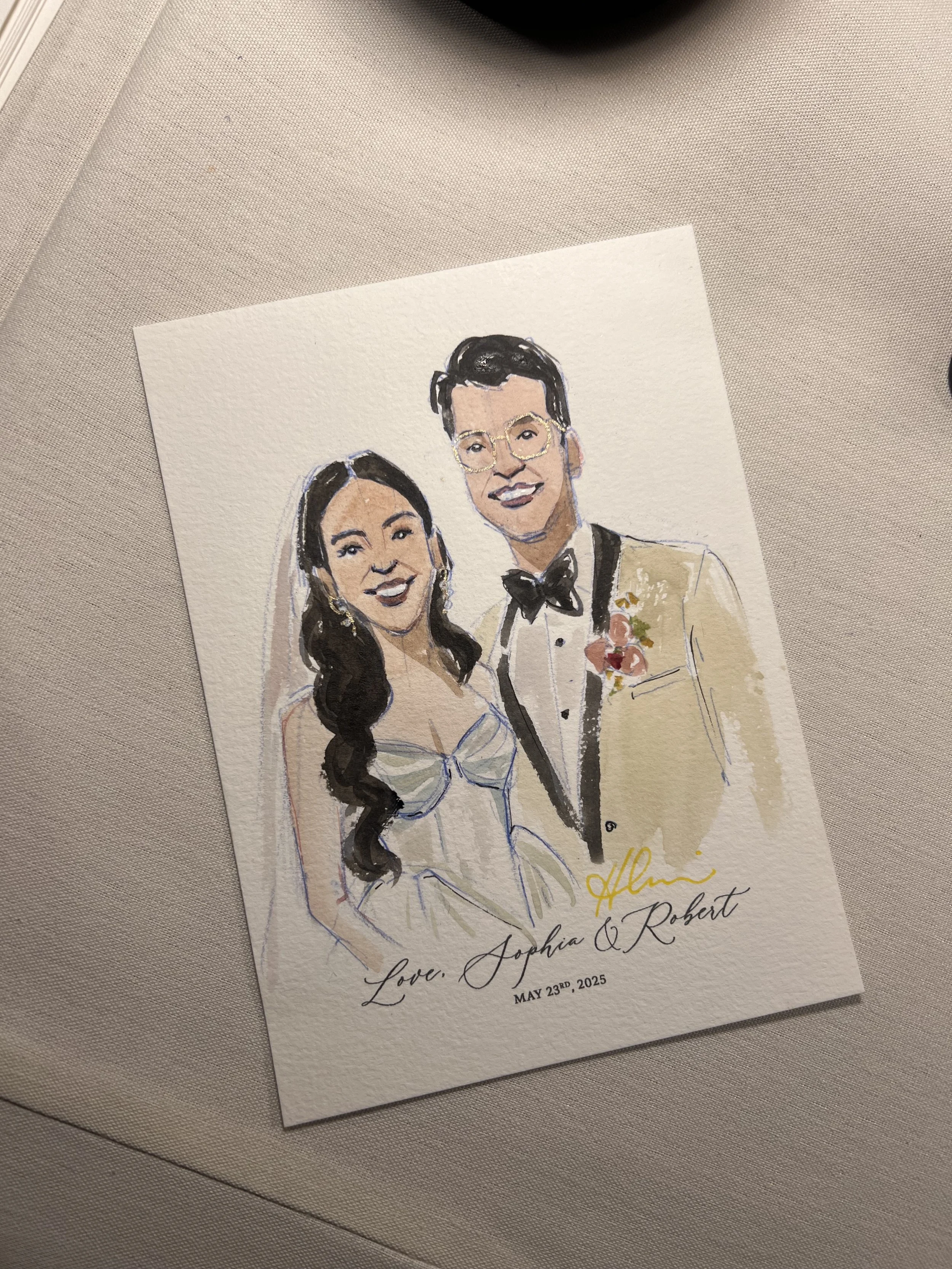 Watercolor illustration of a smiling bride and groom at their wedding, with the bride in a white dress and the groom in a beige tuxedo. The text on the card reads: 'Love, Sophia & Robert, May 23rd, 2025.'