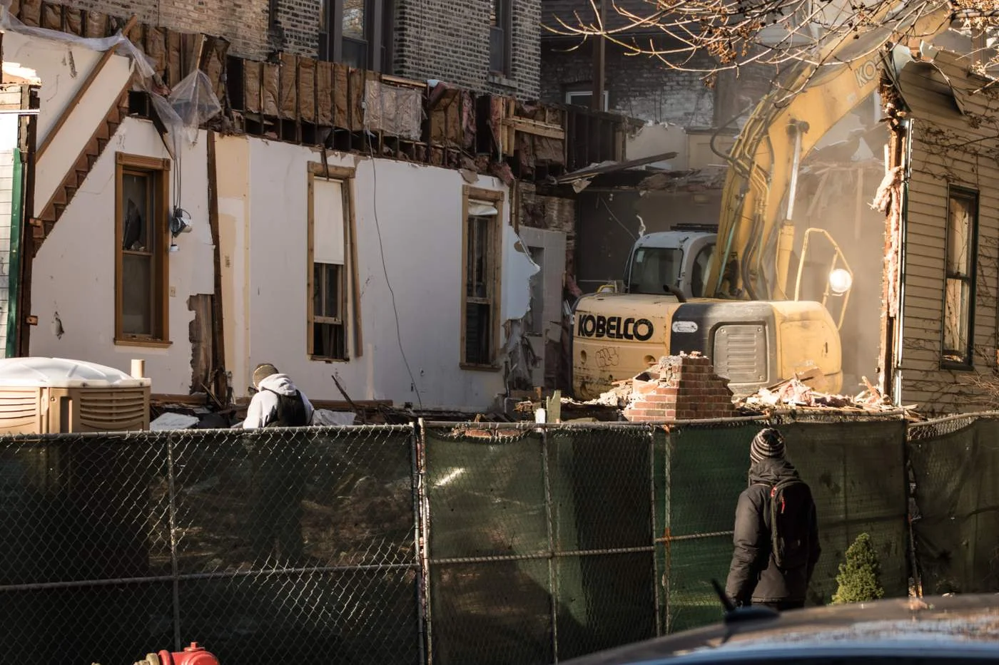 An Uptown resident watches as a residential building is torn down. There is no wet down of the debris (Photo: Manny Ramos).