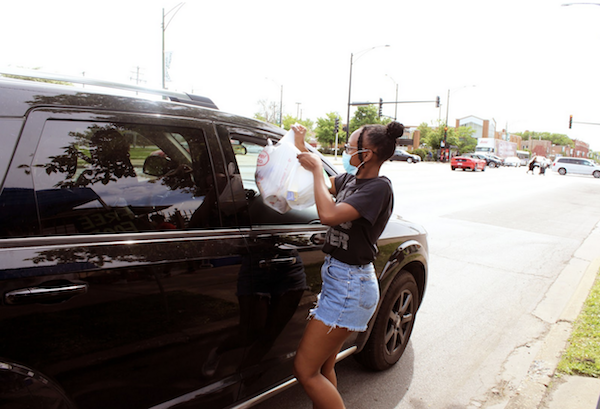  Kyel Brooks hands off groceries at the Oasis on 95th Street food distribution. (Photo: Alex Arriaga/City Bureau) 