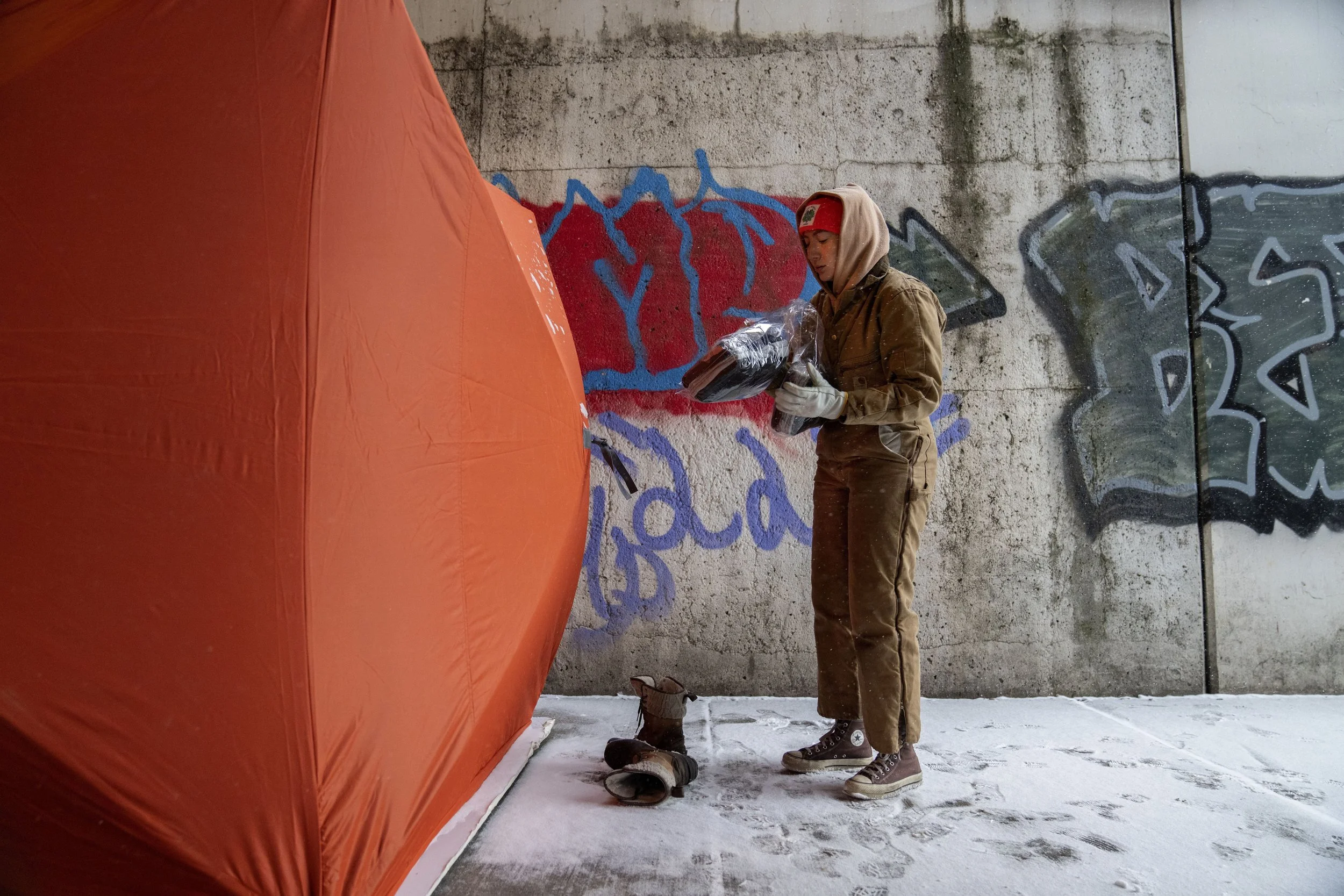 A volunteer drops off clothing and other supplies to an orange tent located near a Chicago underpass.
