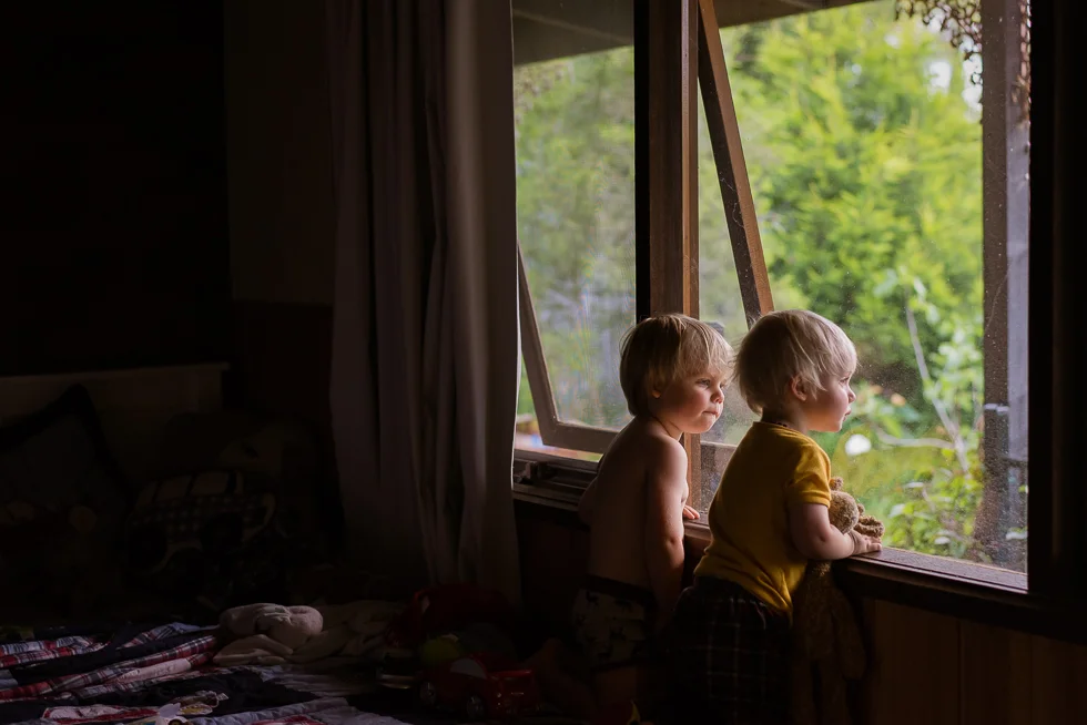 two+brothers+looking+out+bedroom+window+in+beautiful+light+in+melbourne+home+Jenny+rusby+photography+melbourne+family+photographer