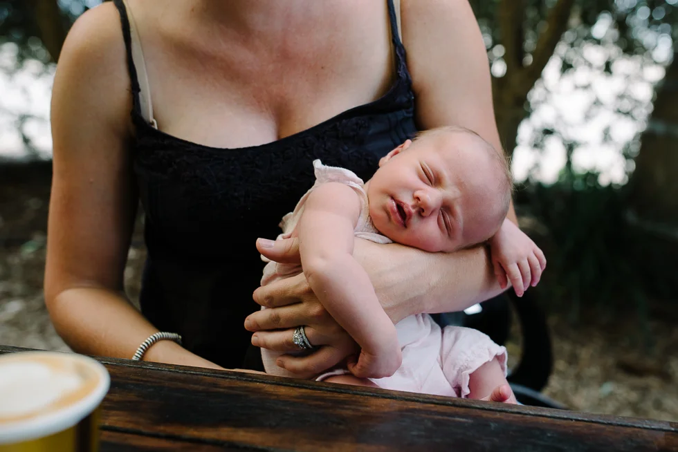 mother+holding+newborn+baby+asleep+on+her+arms+in+melbourne+cafe+melbourne+newborn+photographer+Jenny+rusby+photography