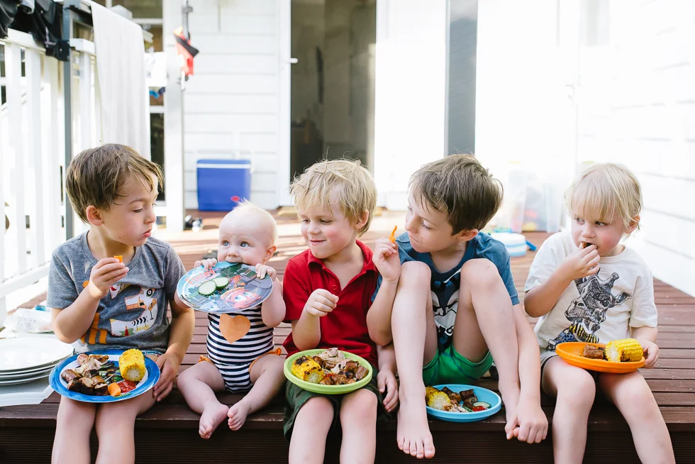 children+eating+dinner+outside+with+baby+eating+her+plate+in+melbourne+summer+Jenny+rusby+photography+melbourne+documentary+photographer