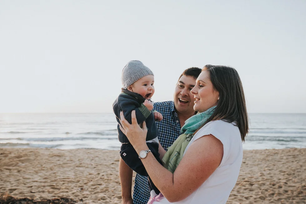 mum+and+dad+holding+smiling+baby+at+beach+melbourne+family+photographer+lifestyle+Jenny+rusby+photography
