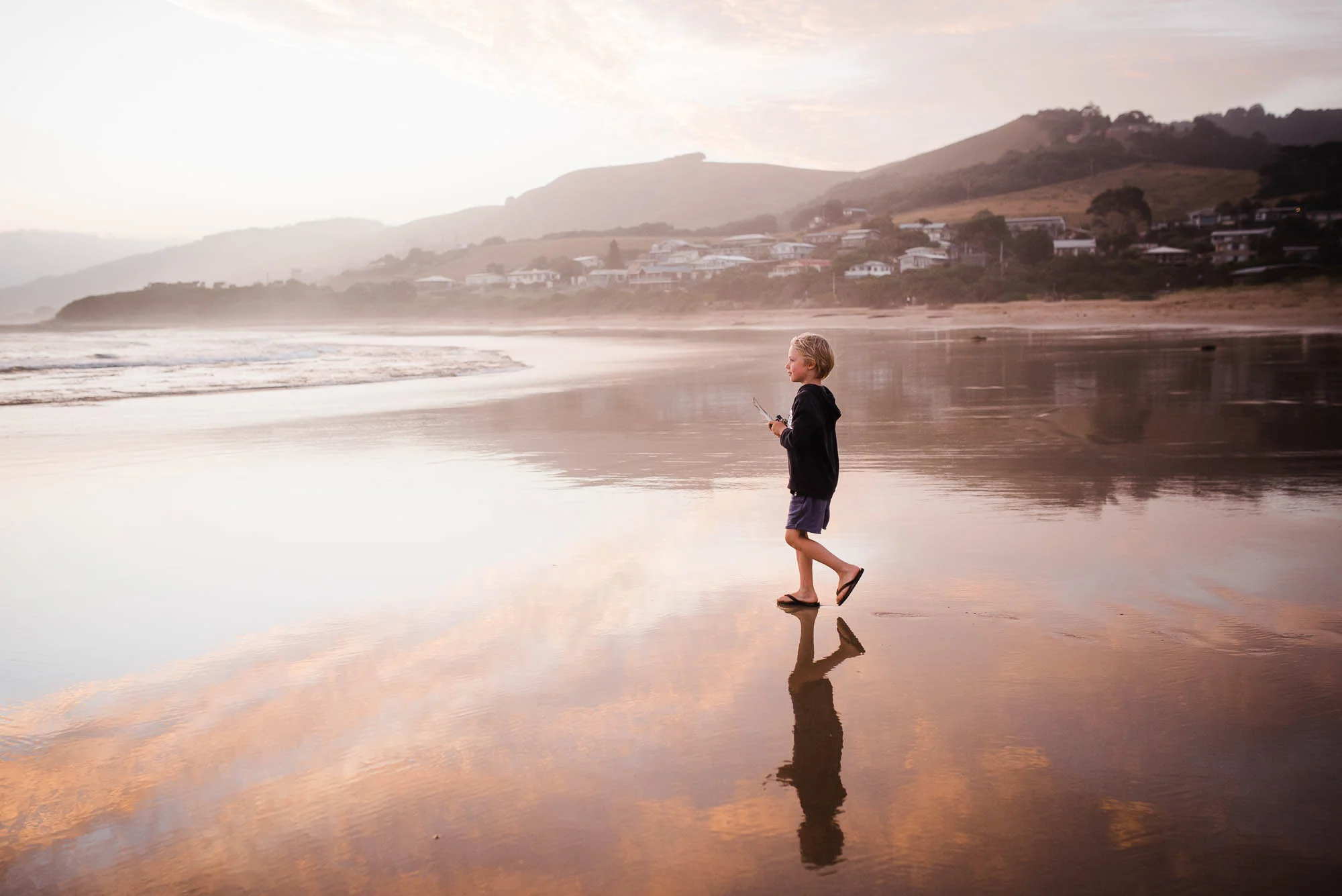 boy+at+the+beach+at+sunset+reflection+pink+sky+clouds+water+melbourne+family+photographer+Jenny+rusby+photography