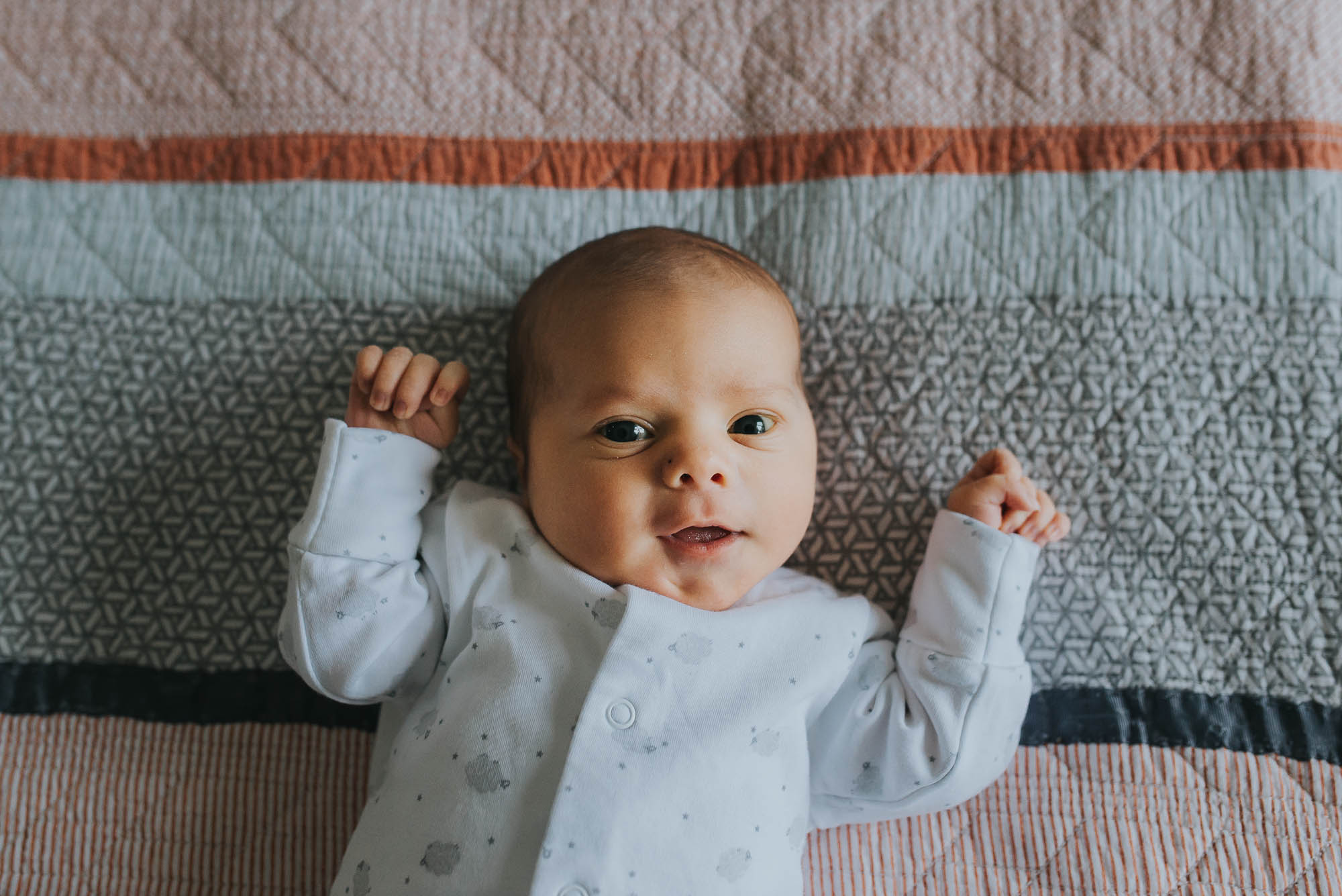 newborn baby smiling on the bed at an in-home newborn baby session