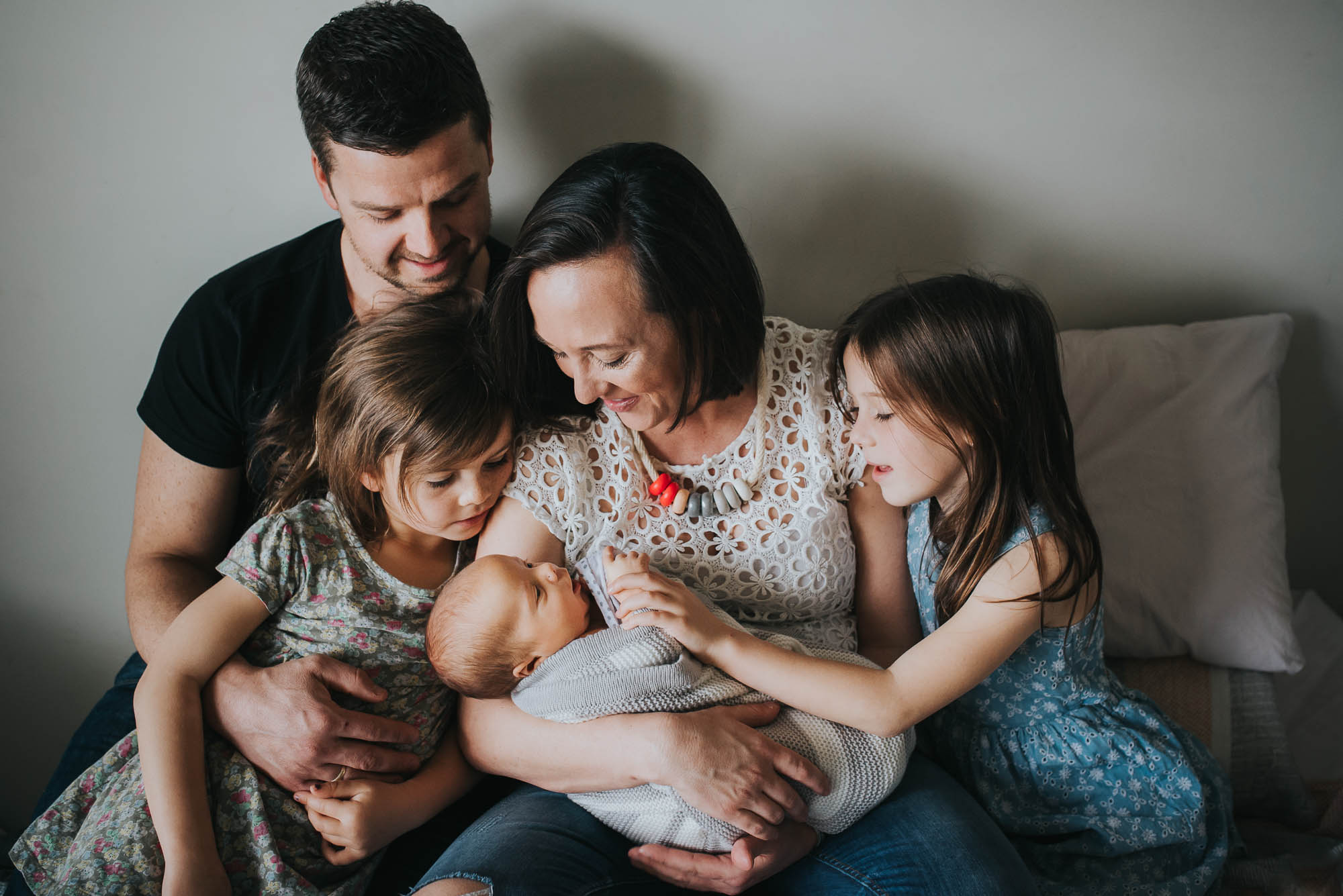 newborn photo session with family snuggling together on the bed looking at the brand new baby