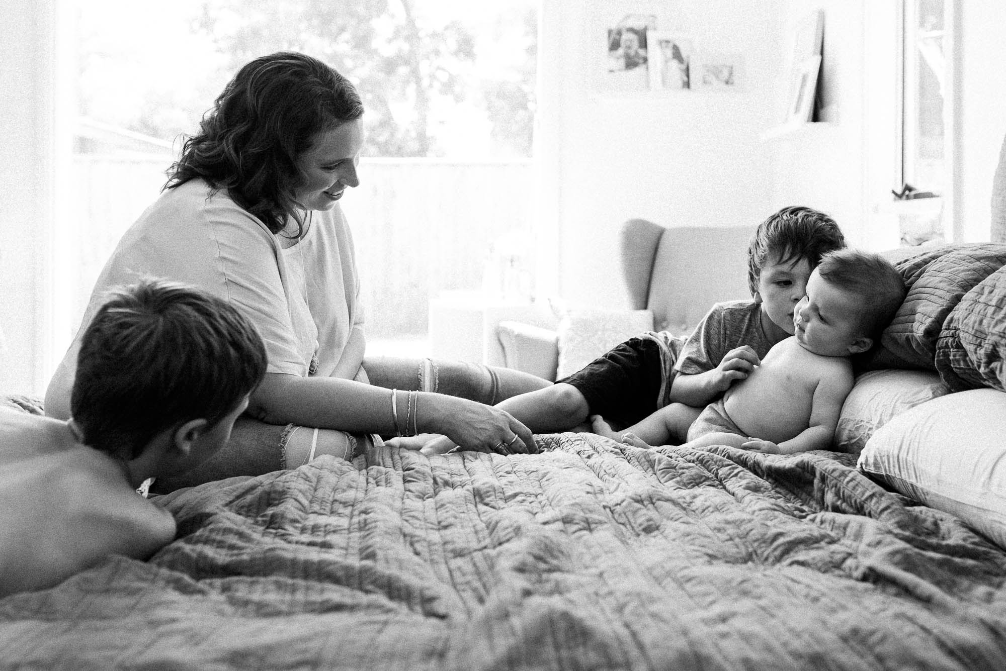 black and white image of mother on bed with four children