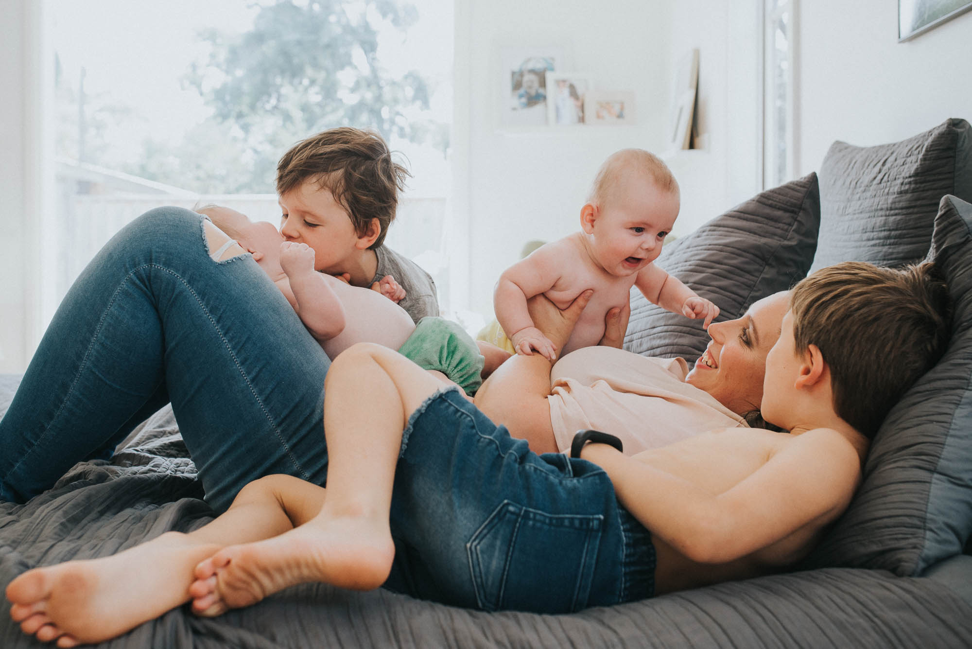 mum laying on bed playing with four children