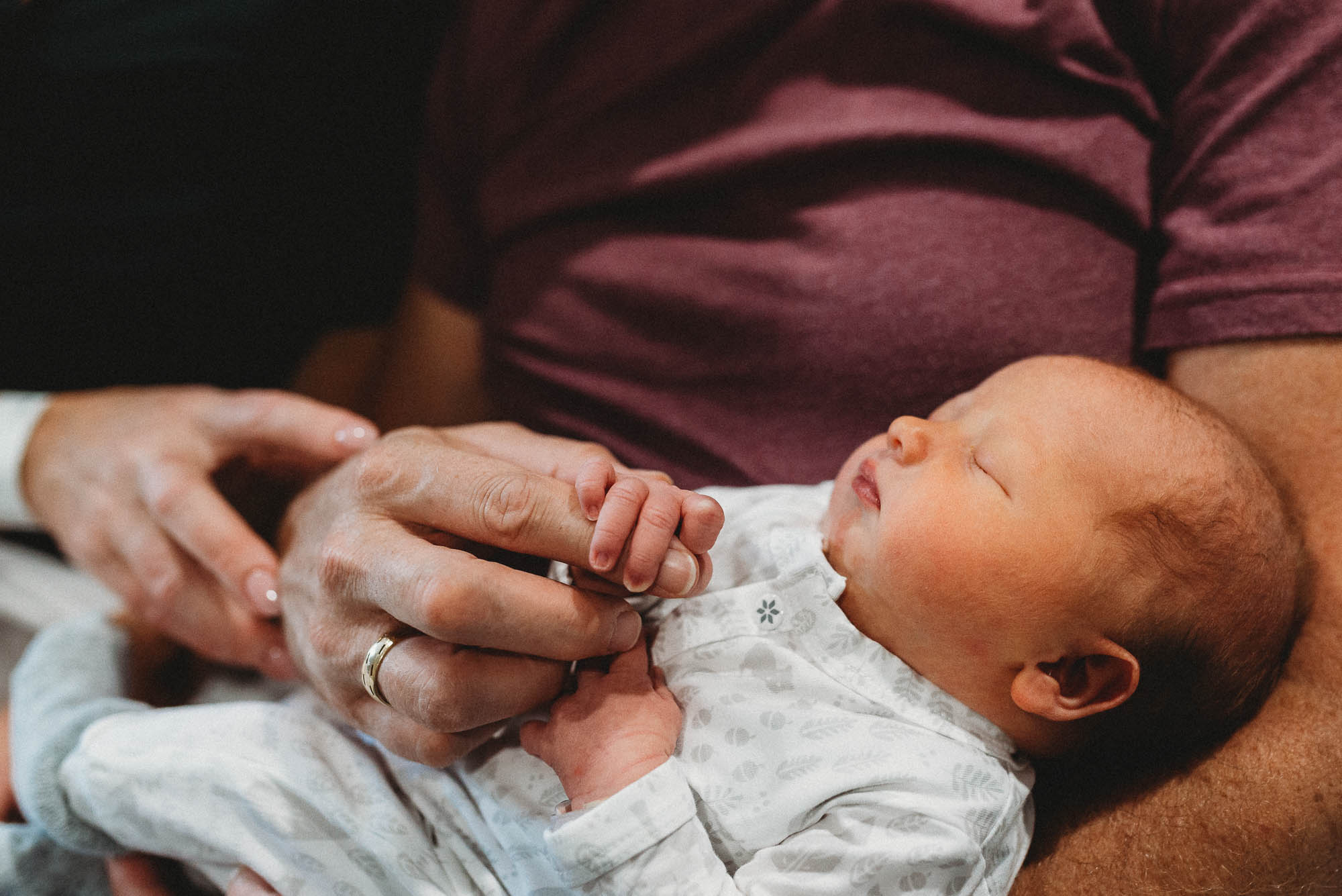dad-holding-newborn-with-hand-clasping-his-finger-melbourne