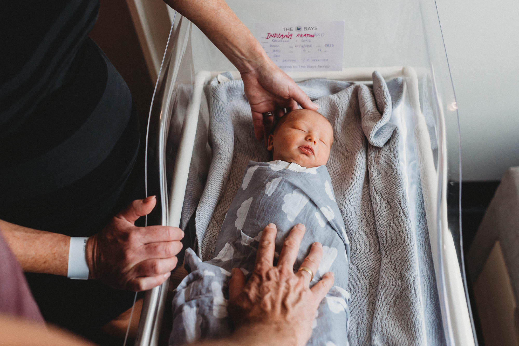 parents-with-hands-on-newborn-at-hosptial-in-bassinet-melbourne