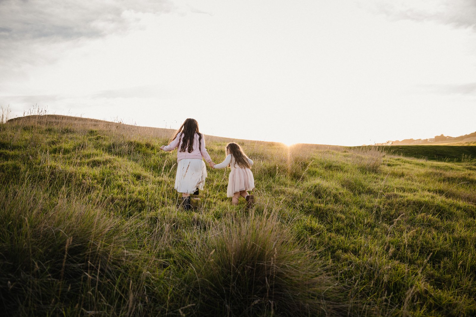 sibling_girls_running_through_field_at_sunset_melbourrne_family_children_photographer-1.jpg