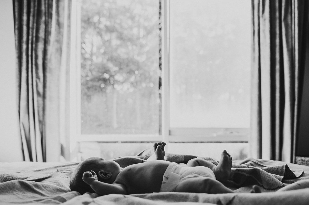 baby_laying_on_bed_at_home_black_and_white_lifestyle_famiily_photogapher.jpg