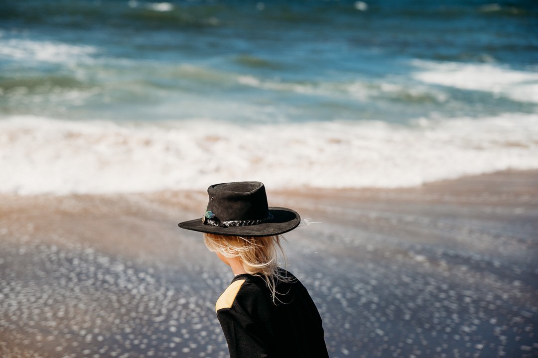 child_at_beach__wind_hair_blowing_waves_hat_melbourne_family_photographer.jpg
