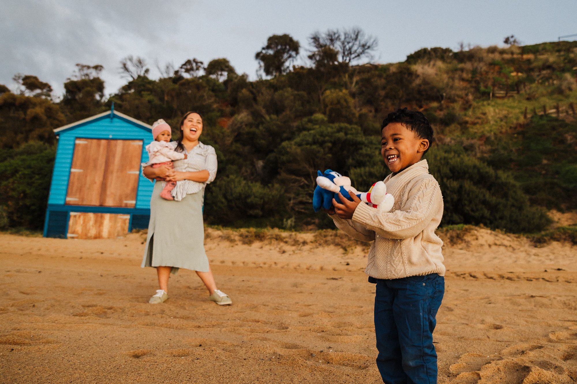boy_laughing_holding_sonic_toy_mum_sisteer_laughing_beach_sunset_melbourne_family_photographer_jenny_rusby-1.jpg