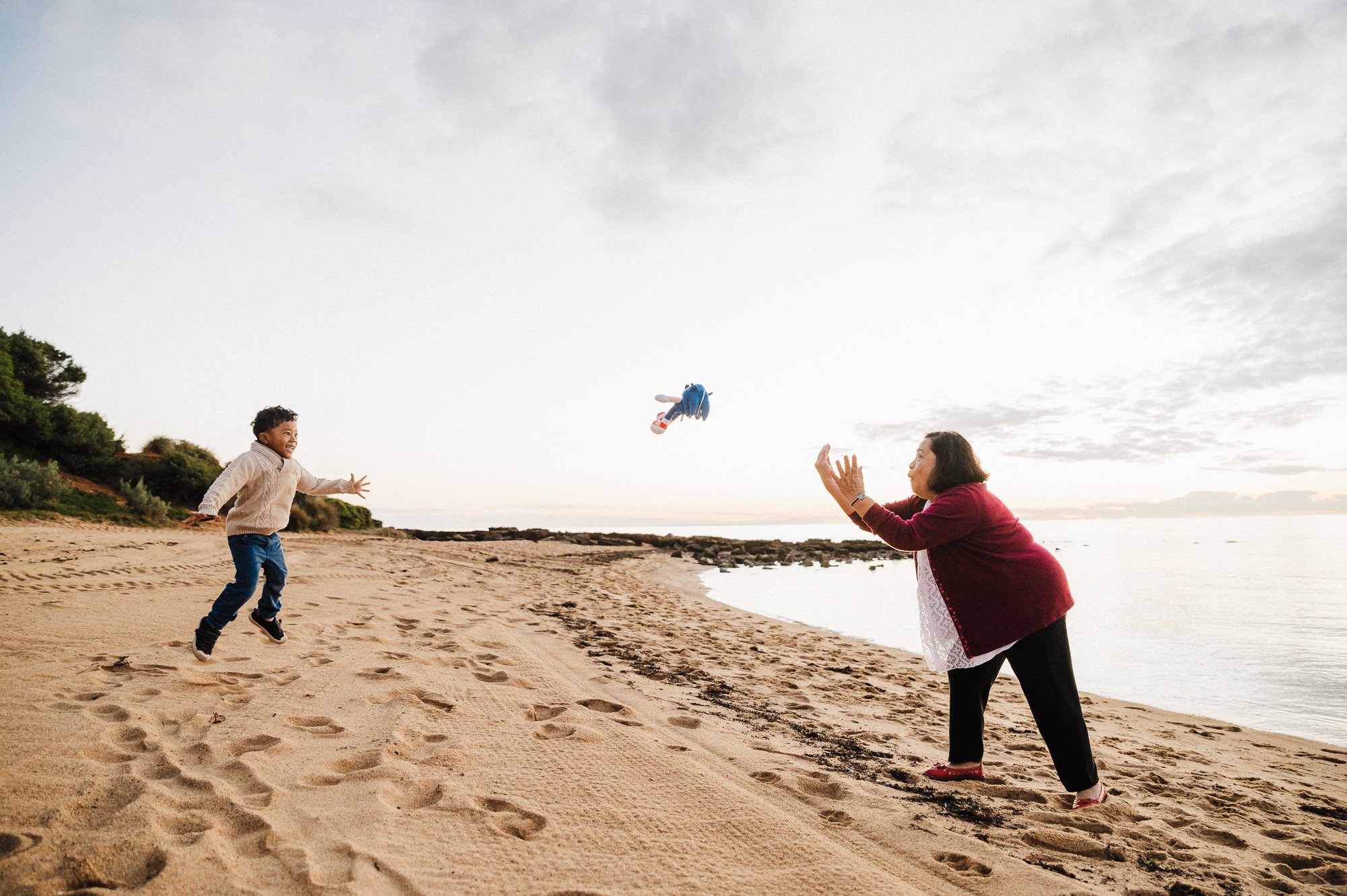 boy_tossing_sonic_toy_to_grandma__smiling_laughing_beach_sunset_melbourne_family_photographer_jenny_rusby-1.jpg
