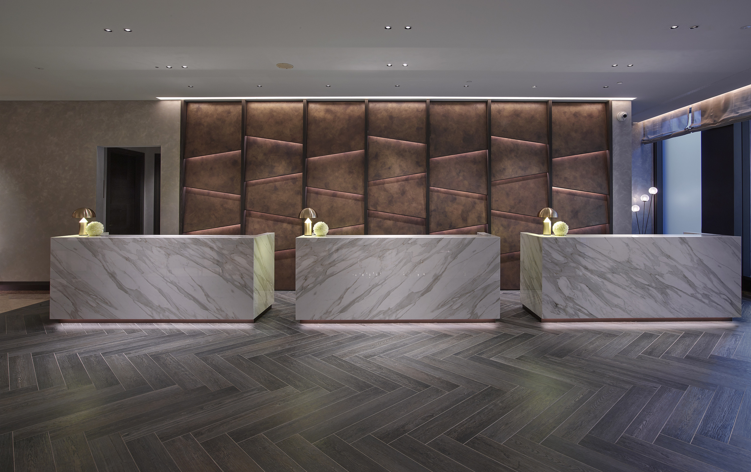 Reception Desks in Neolith Calacatta Gold bookmatch Neolith, rear panels in Oikos Bronze