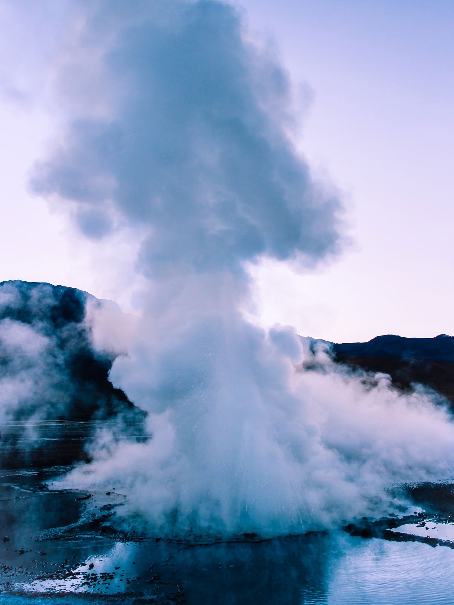 Geyser eruption at el tatio geyser field in chile during blue ho