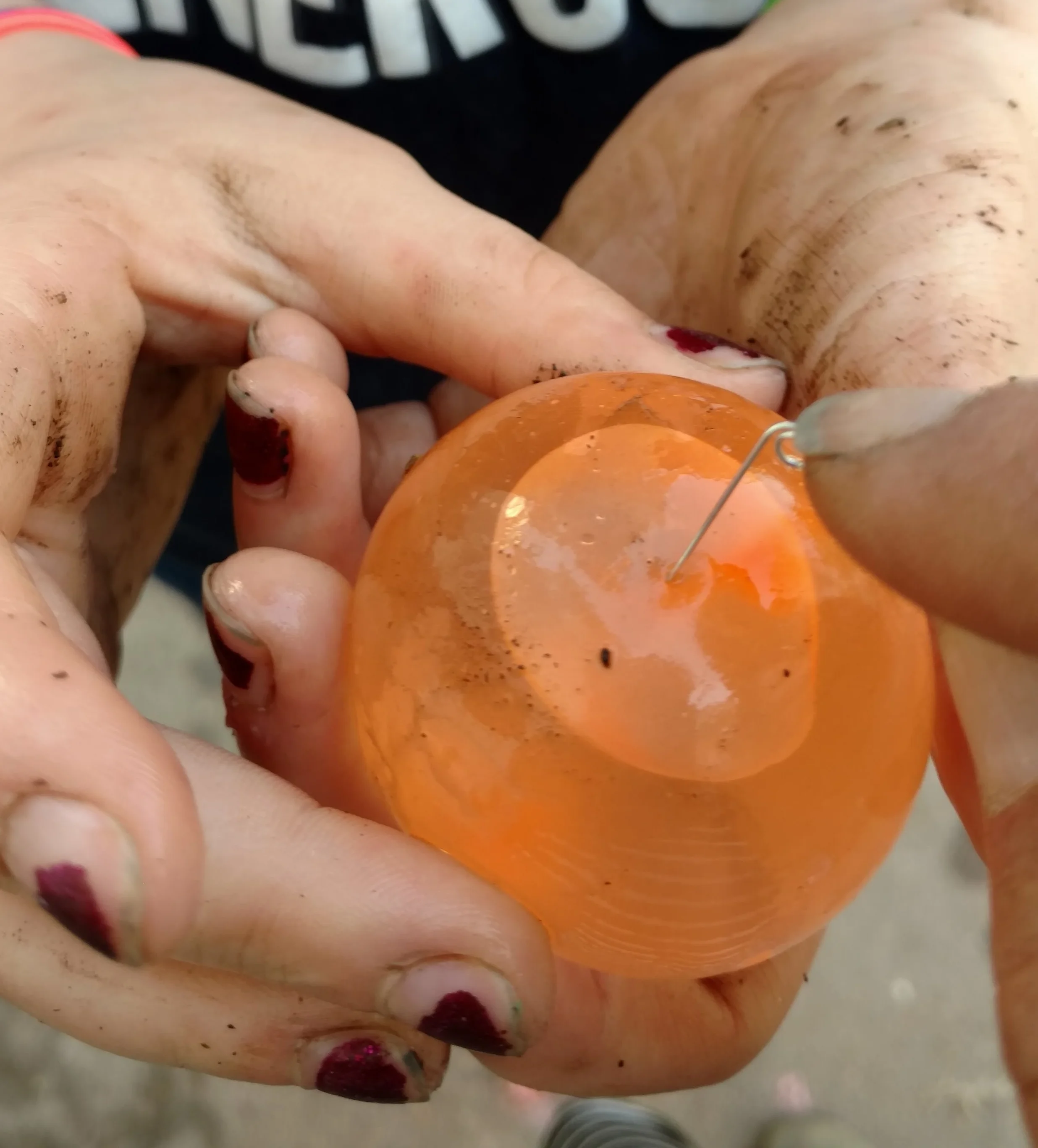 Use a pin to pierce the water balloon over the pocket of air.