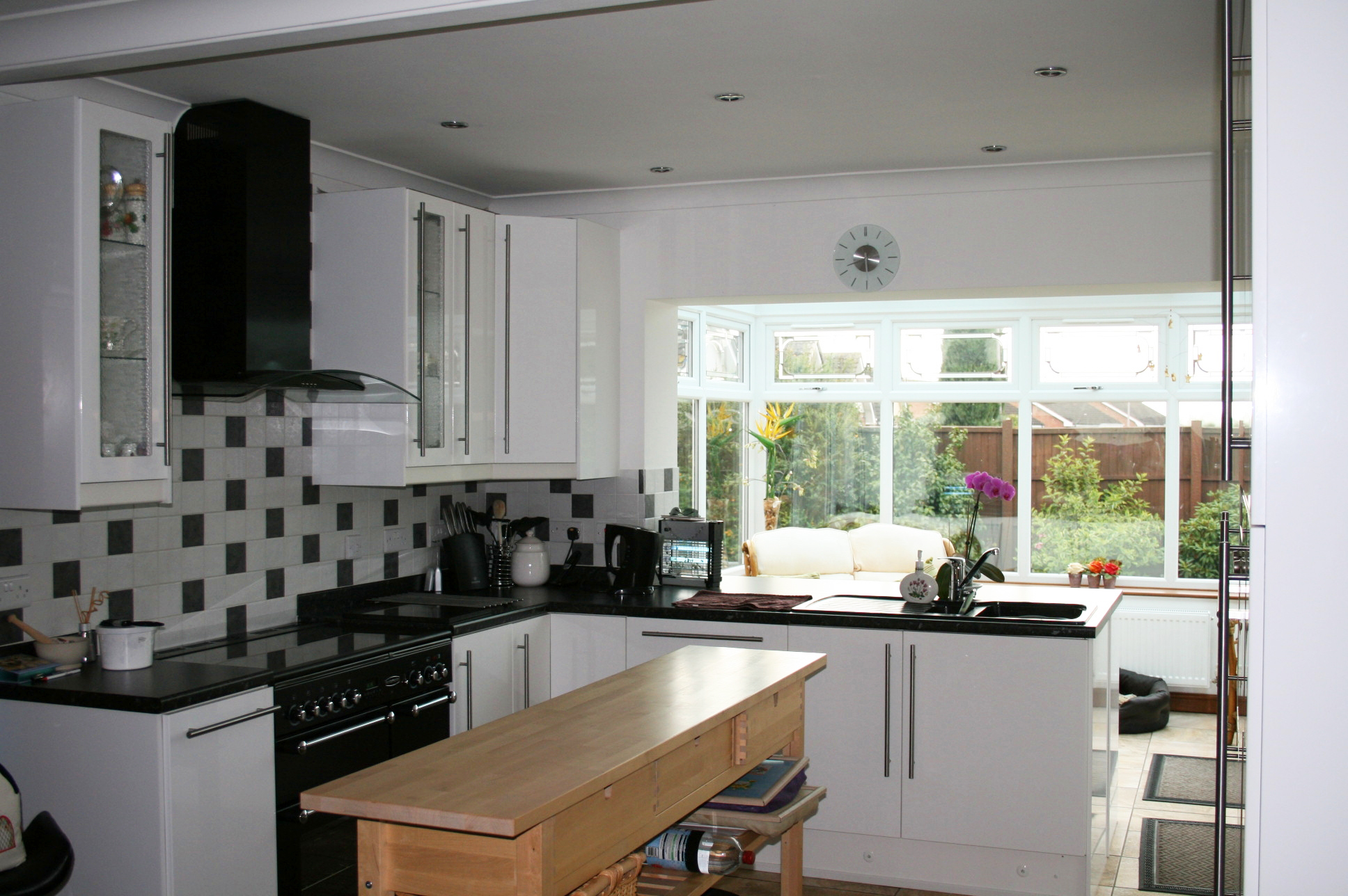 Cream gloss kitchen with integrated handles and blackstone worktops.