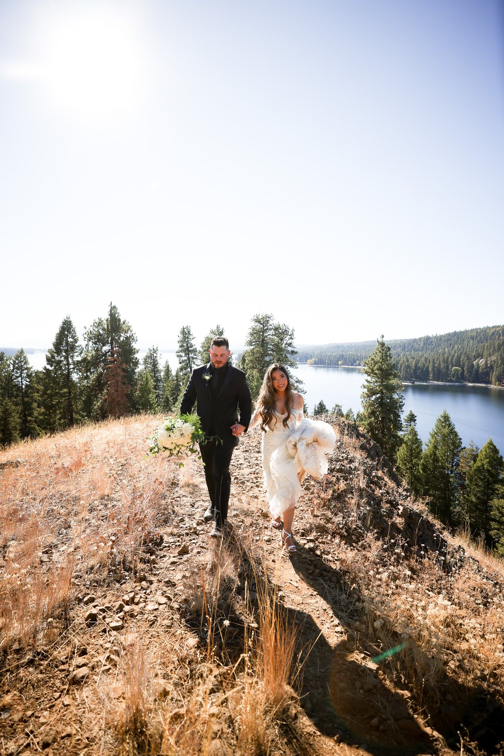 Groom and Bride walk hand in hand in mountains