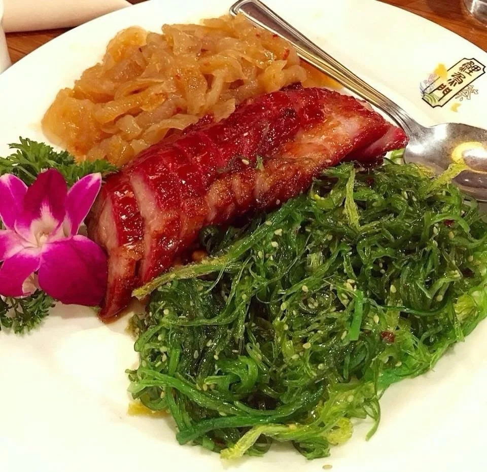The classic Cantonese cold appetizer trio at Koi Palace: a thick slice of lacquered char siu, a mound of marinated jellyfish, and a sesame-scattered seaweed salad &mdash; three textures, three temperatures, all on one plate. The pork is rich and glos