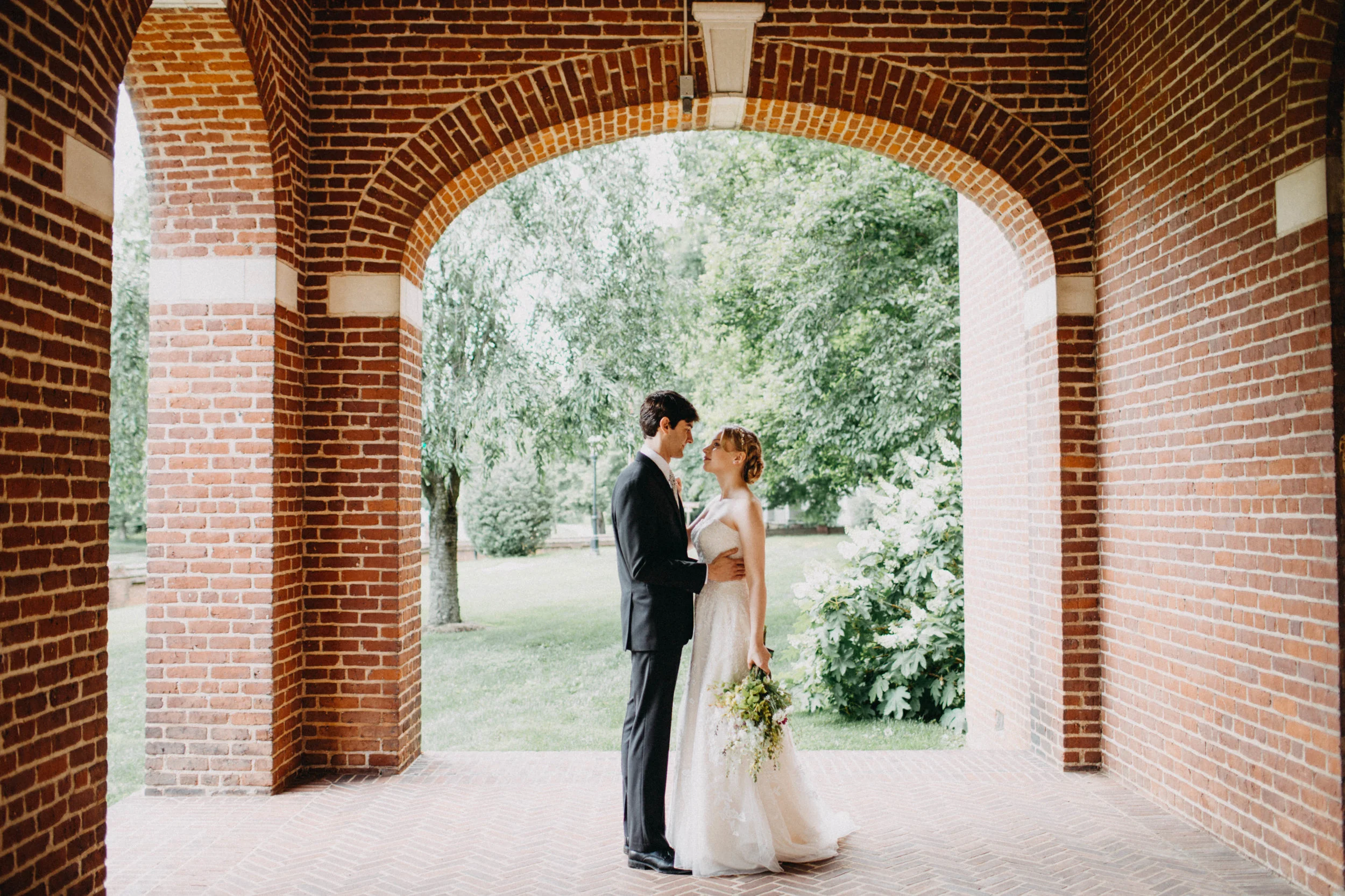 Portrait of couple standing together under brick arch.