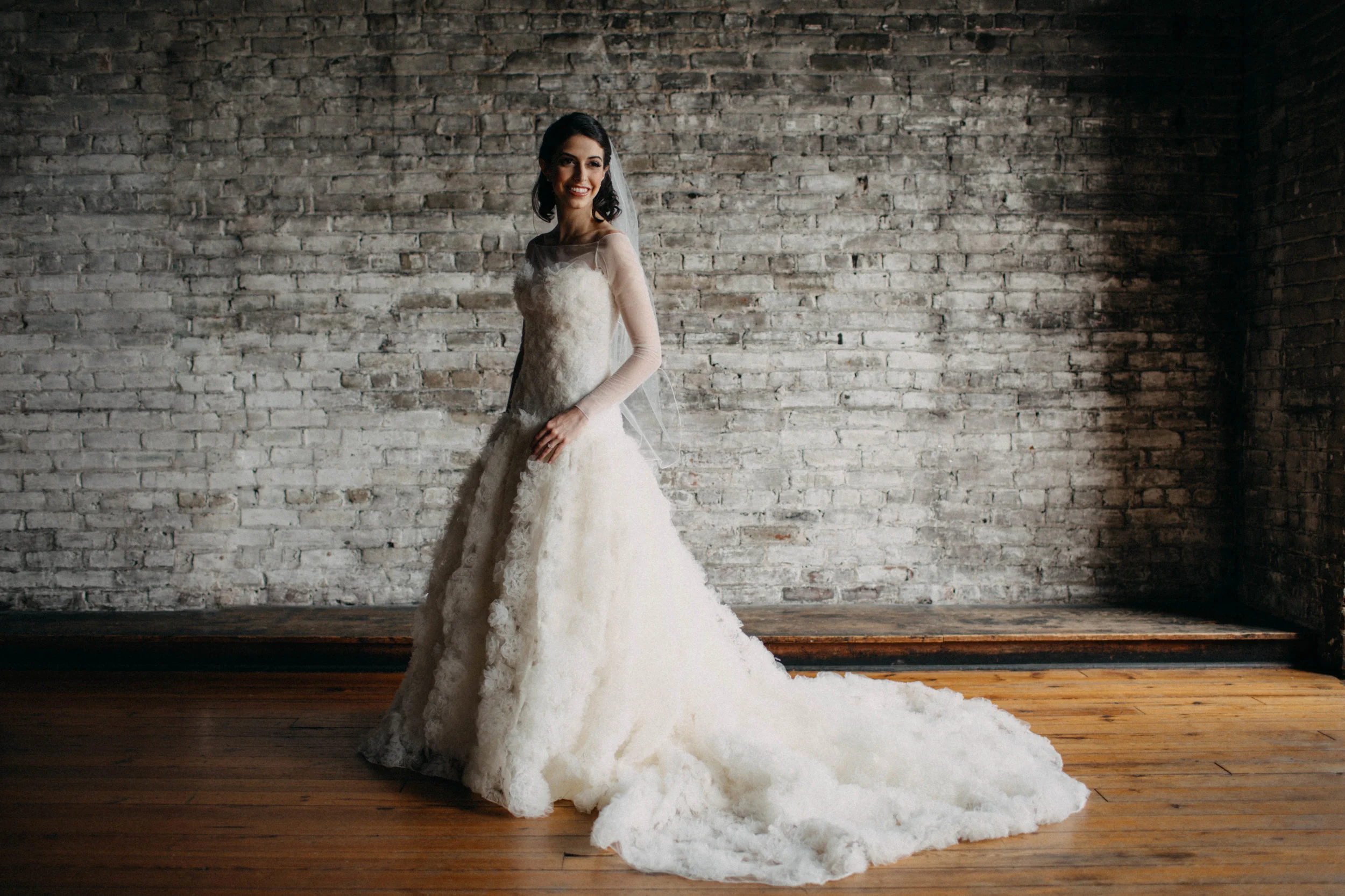 Portrait of bride standing in front of brick wall.