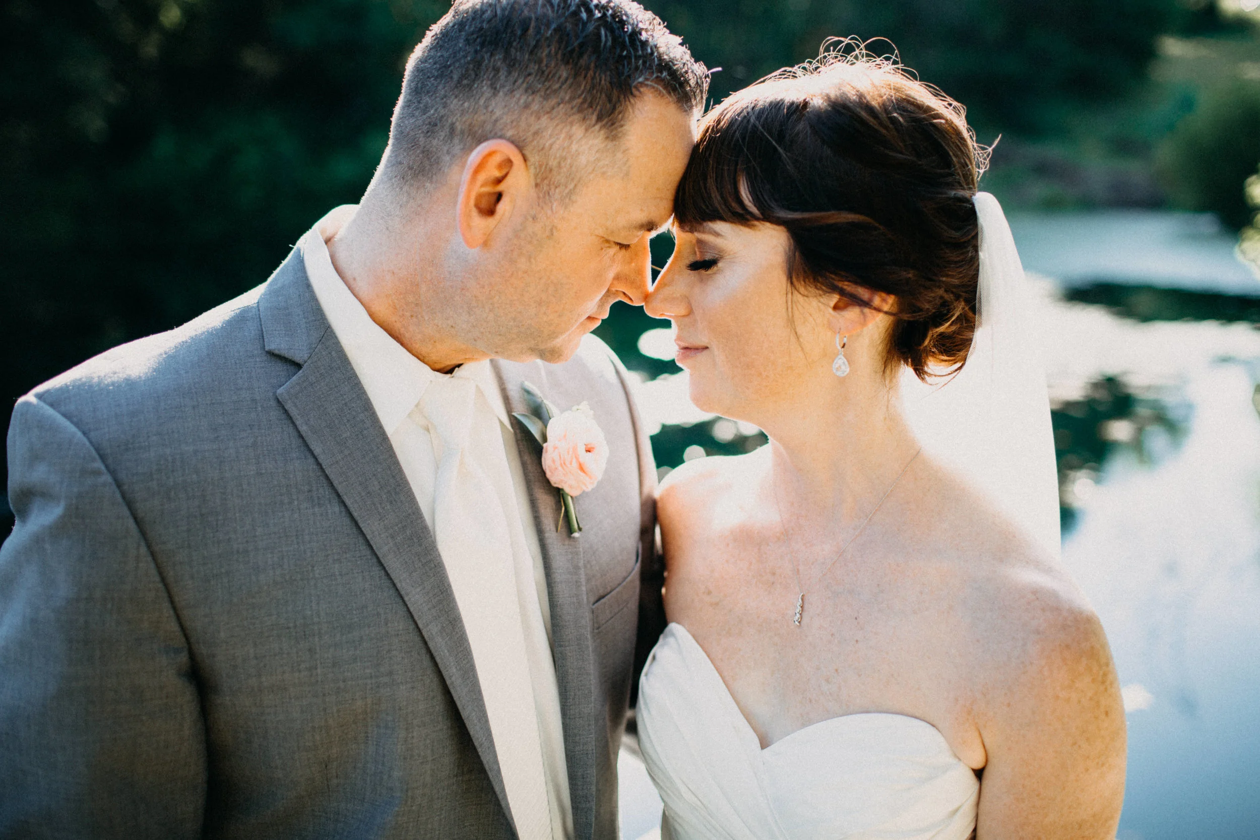 Portrait of couple embracing beside pond.